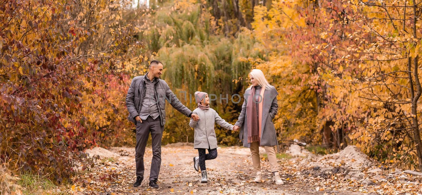 A Family of four enjoying golden leaves in autumn park by Andelov13