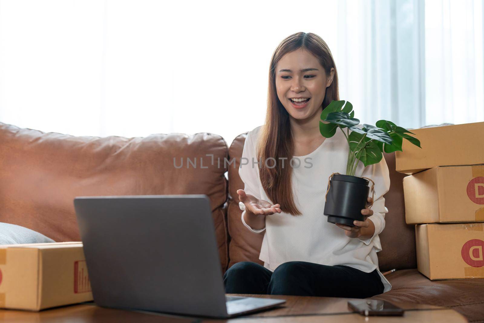 A female entrepreneur selling plants via live streaming laptop computer and checking orders from customer for online shopping concept. by nateemee