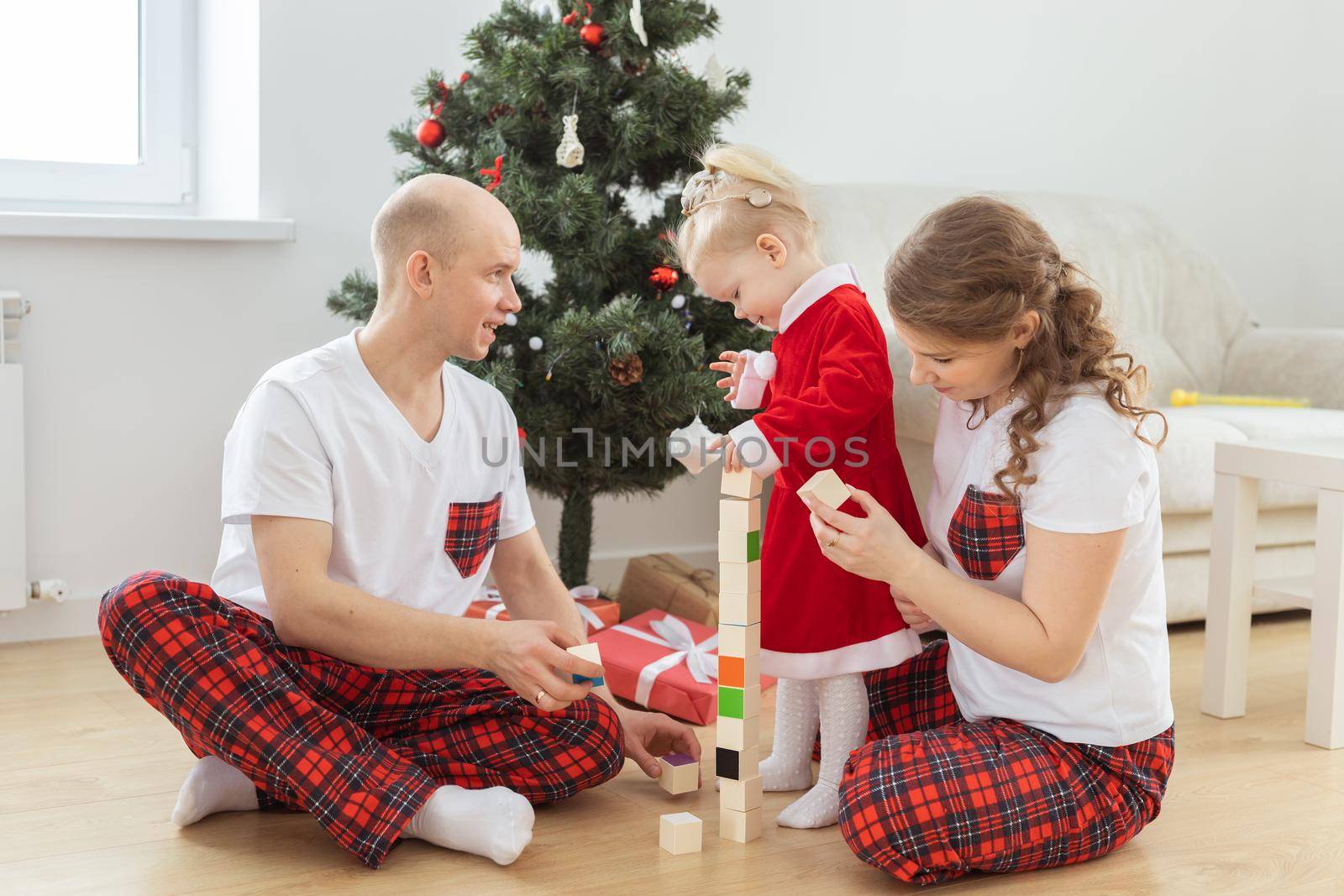 Baby child with hearing aid and cochlear implant having fun with parents in christmas room. Deaf , diversity and health and diversity by Satura86