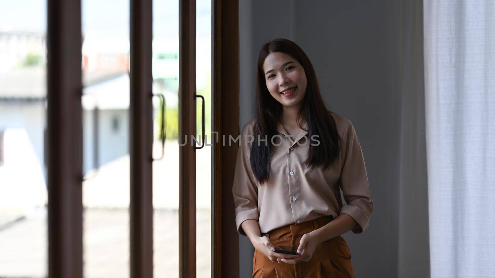 Portrait of confident asian businesswoman standing in office and smiling to camera.