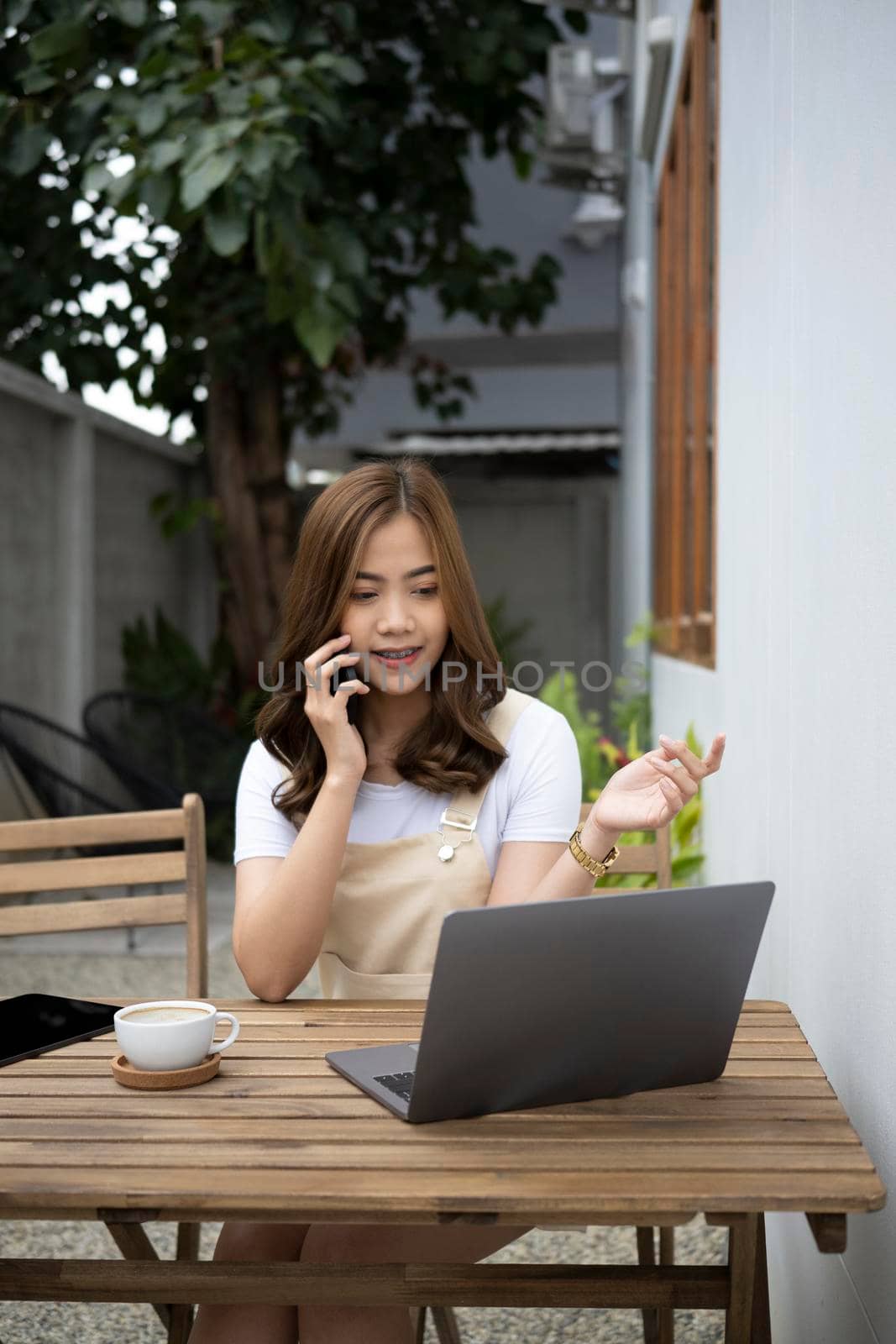 Young asian woman sitting outdoor cafe and talking on mobile phone.