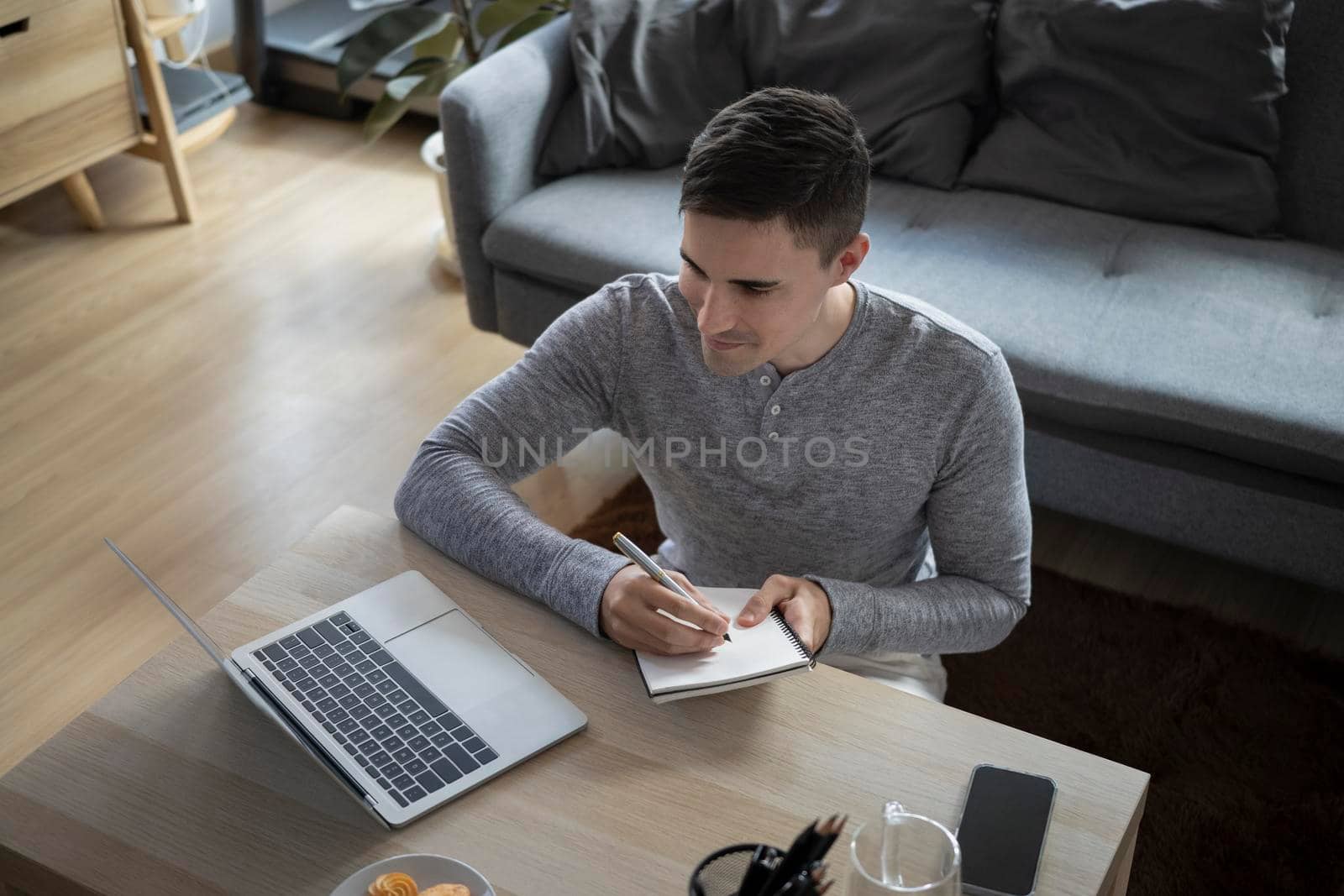 Man freelancer sitting in living room and working with laptop computer.