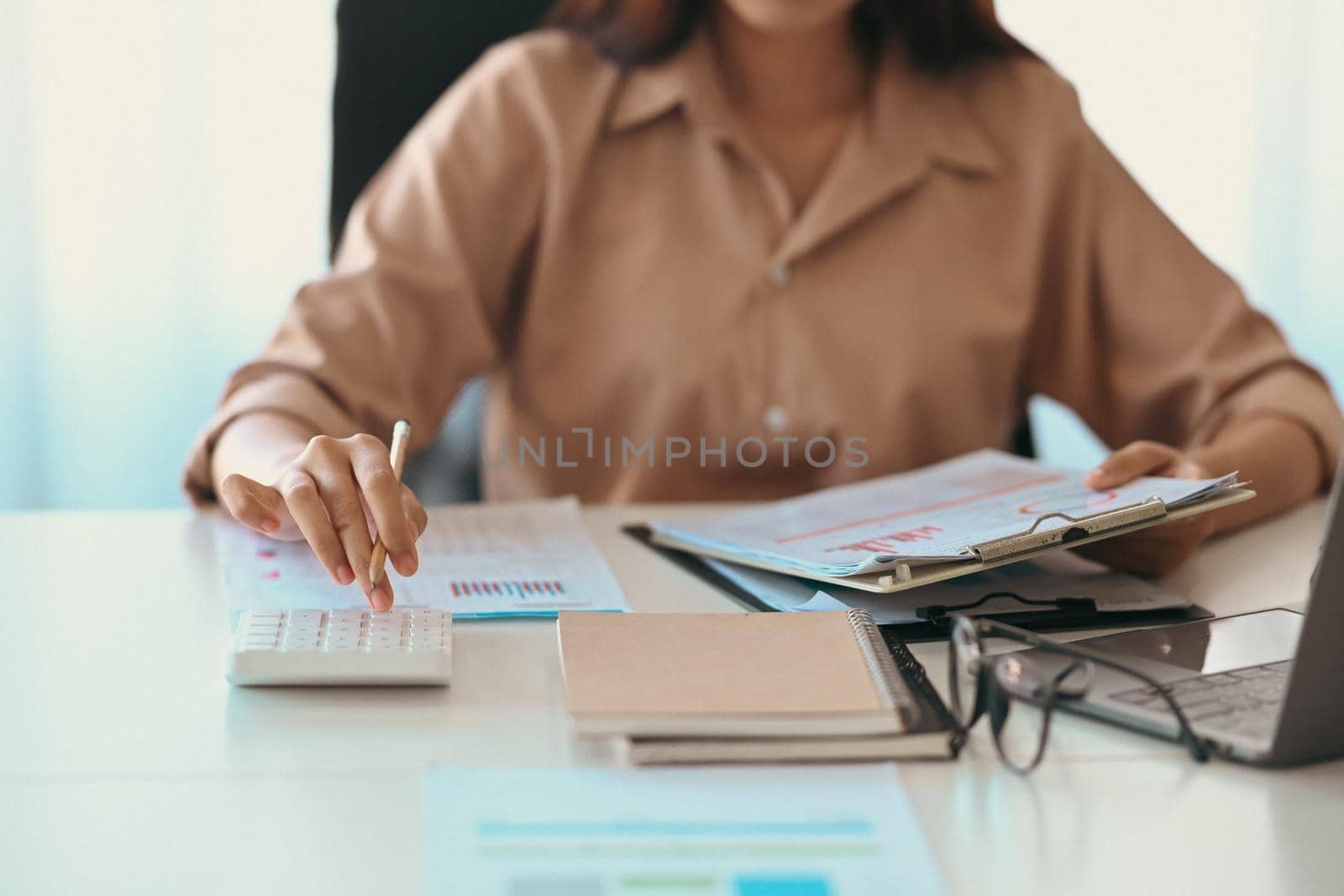 Cropped shot businesswoman holding financial document and using calculator.