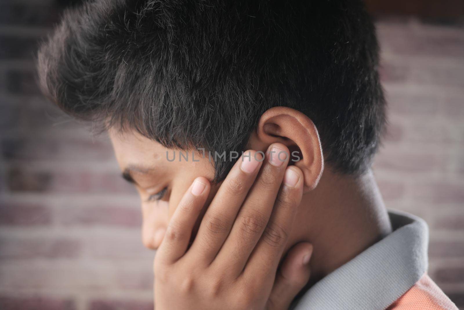 teenage boy having ear pain touching his painful ear