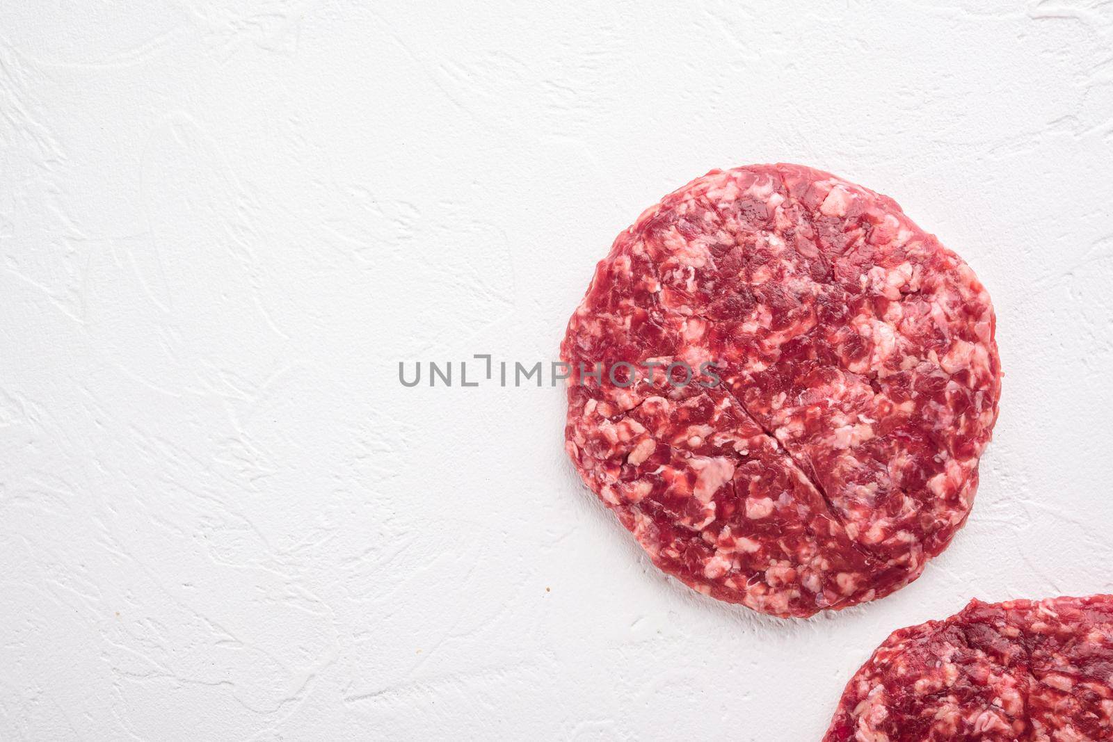 Raw Ground beef meat Burger steak cutlets, on white stone background, top view flat lay, with copy space for text by Ilianesolenyi