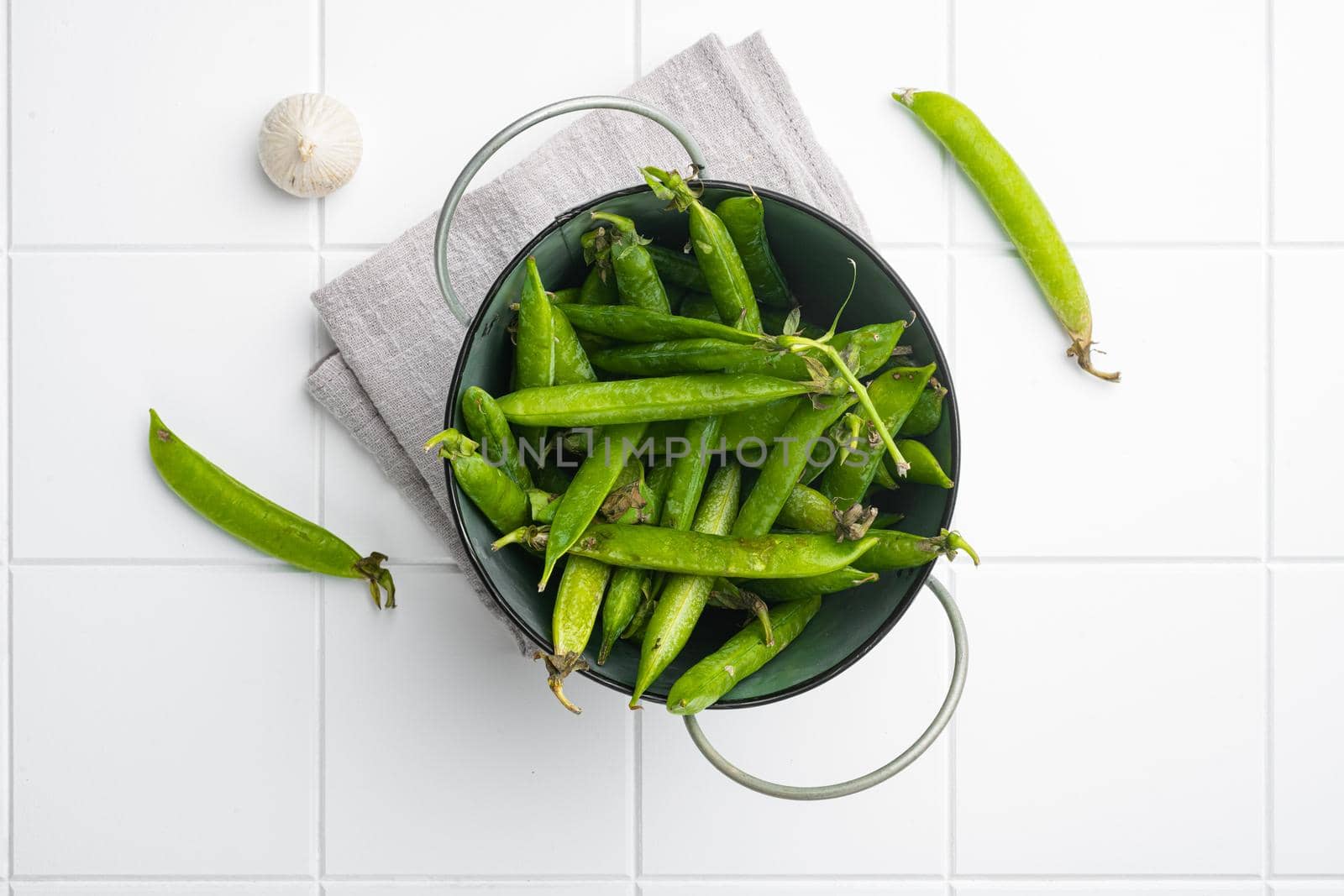 Green pea pod on white ceramic squared tile table background, top view flat lay by Ilianesolenyi