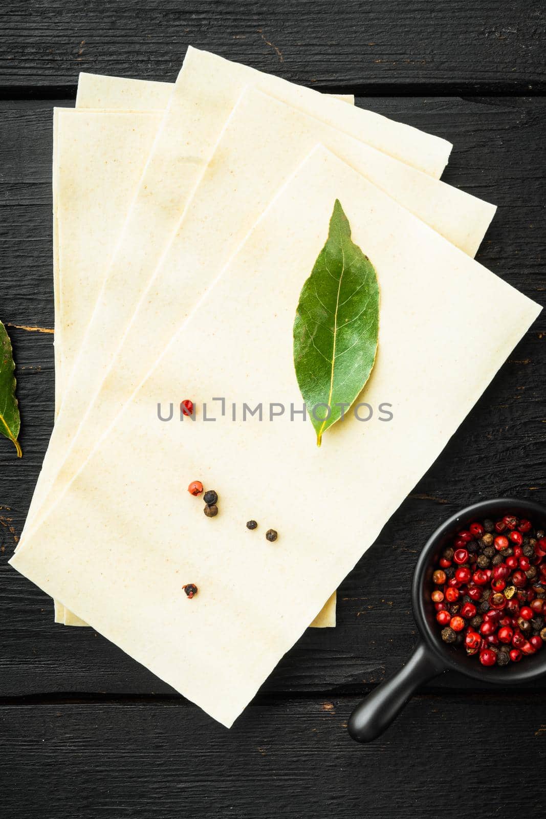 Organic lasagna pasta sheets set, with seasoning and herb, on black wooden table background, top view, flat lay