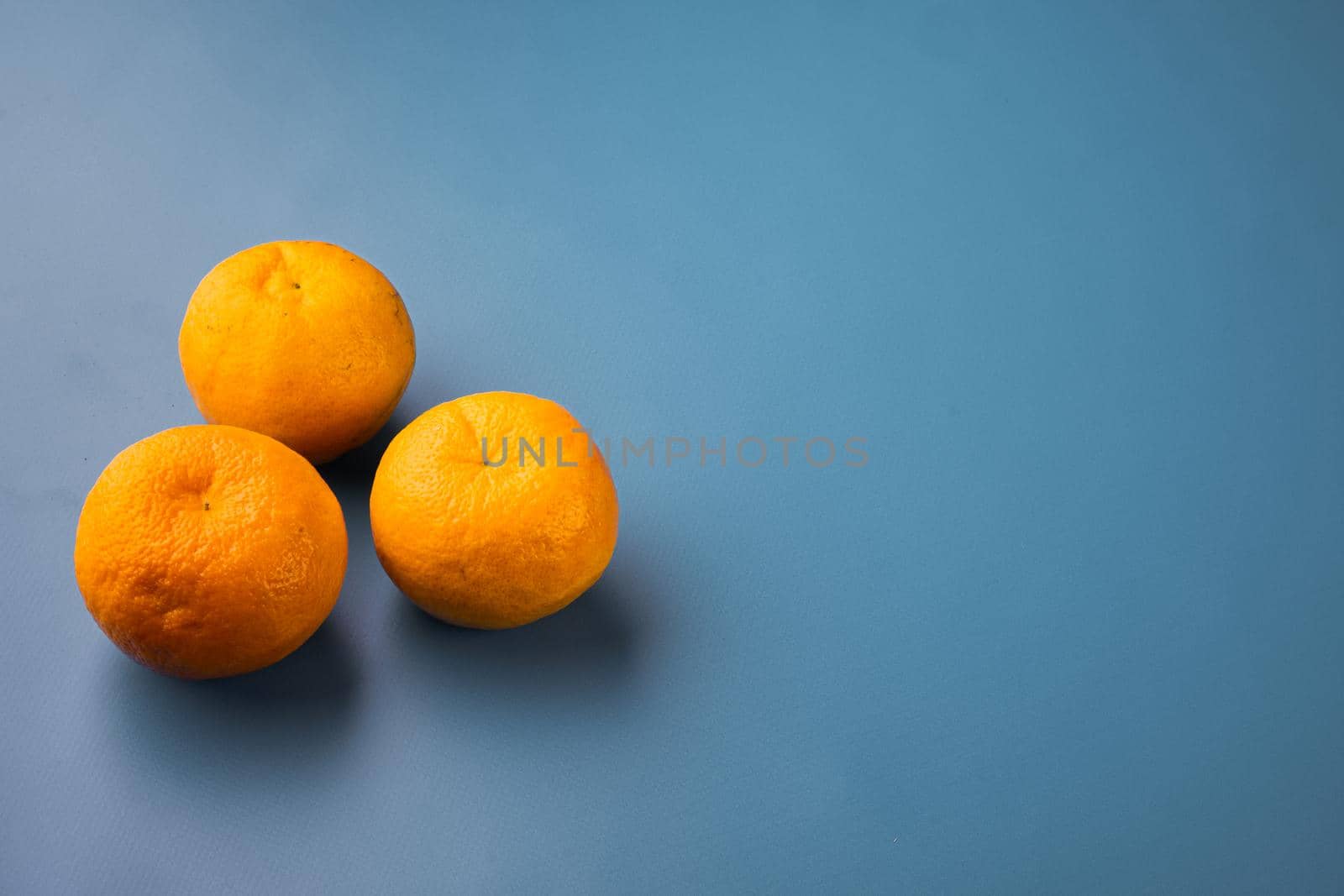 Fresh organic orange fruit, on blue textured summer background, with copy space for text by Ilianesolenyi