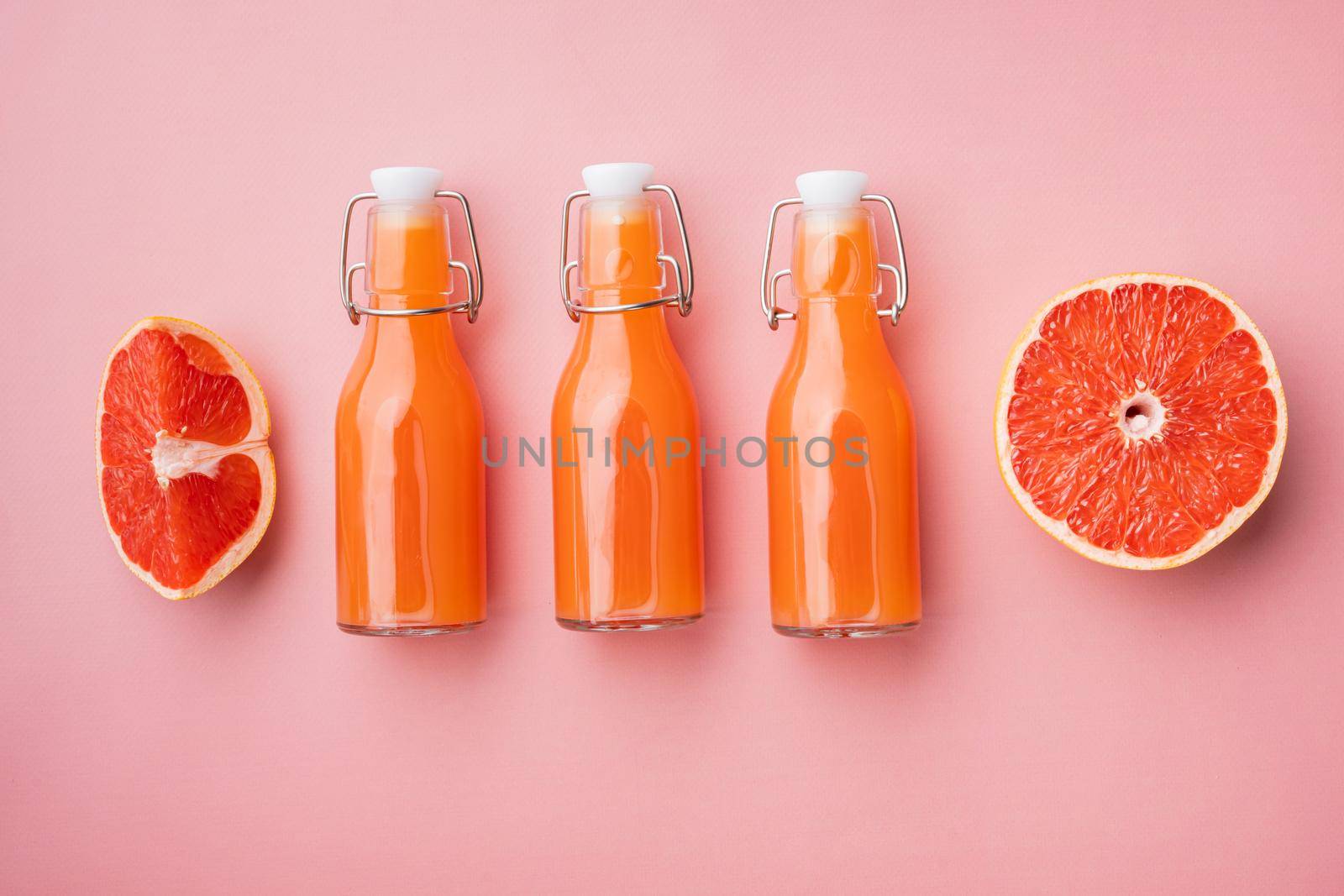 Freshly squeezed grapefruit juice set, on pink textured summer background, top view flat lay