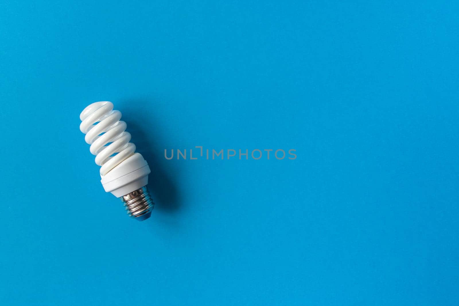 Energy saving light bulb on a blue background. Economical consumption of electricity. The concept of nature conservation