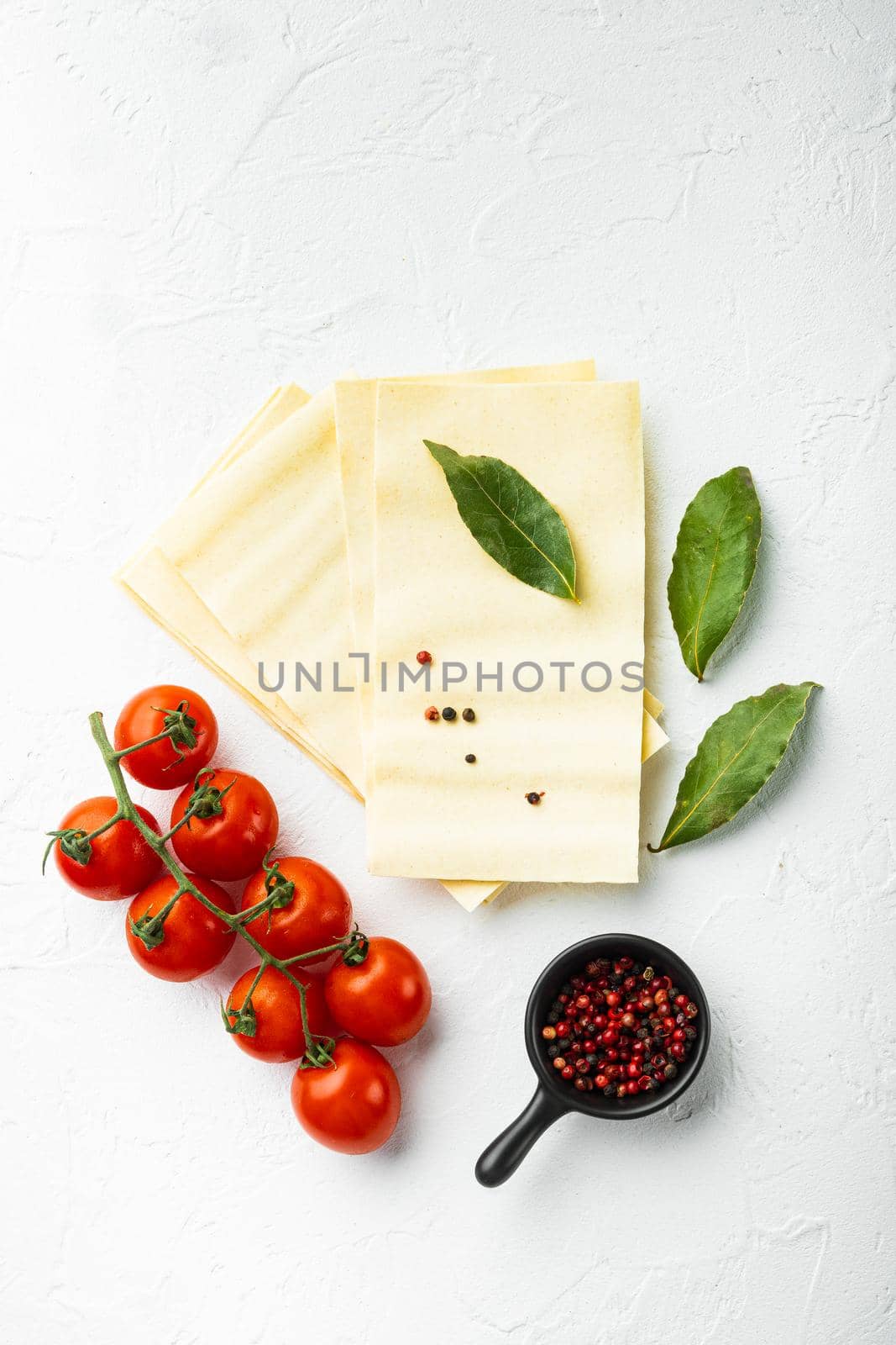 Dried uncooked lasagna pasta sheets set, with seasoning and herb, on white stone background, top view, flat lay