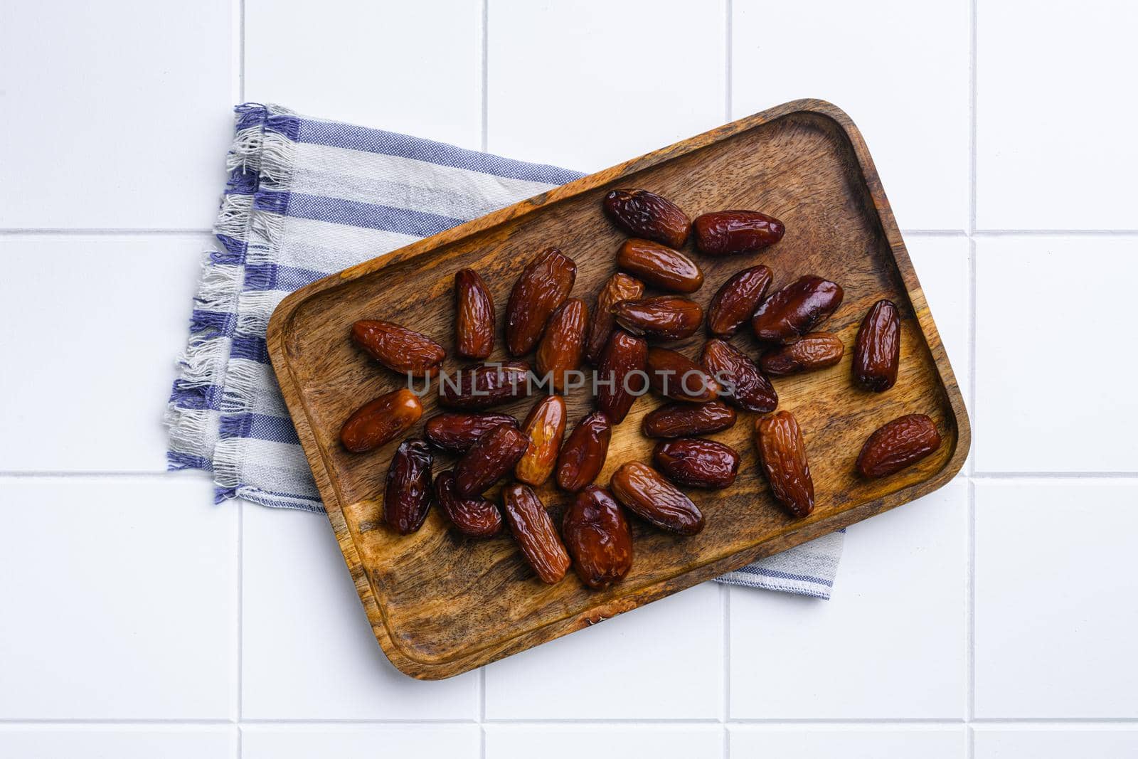 Traditional arabic dry dates set, on white ceramic squared tile table background, top view flat lay by Ilianesolenyi
