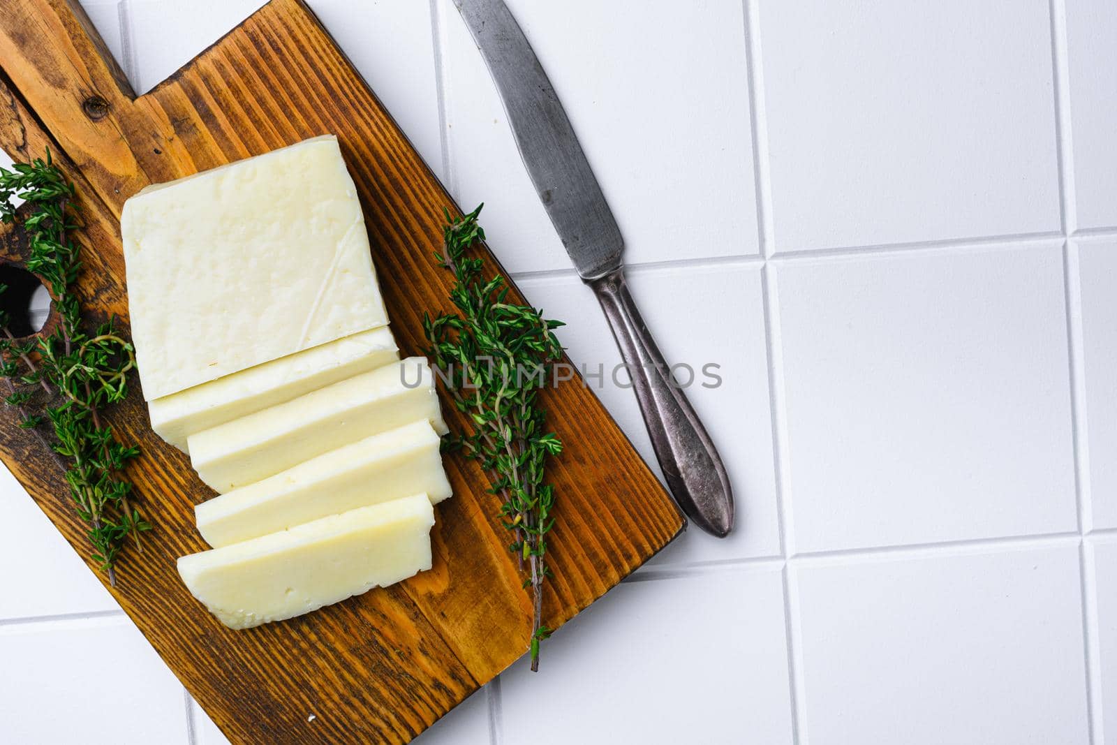 Fresh halloumi cheese, on white ceramic squared tile table background, top view flat lay, with copy space for text