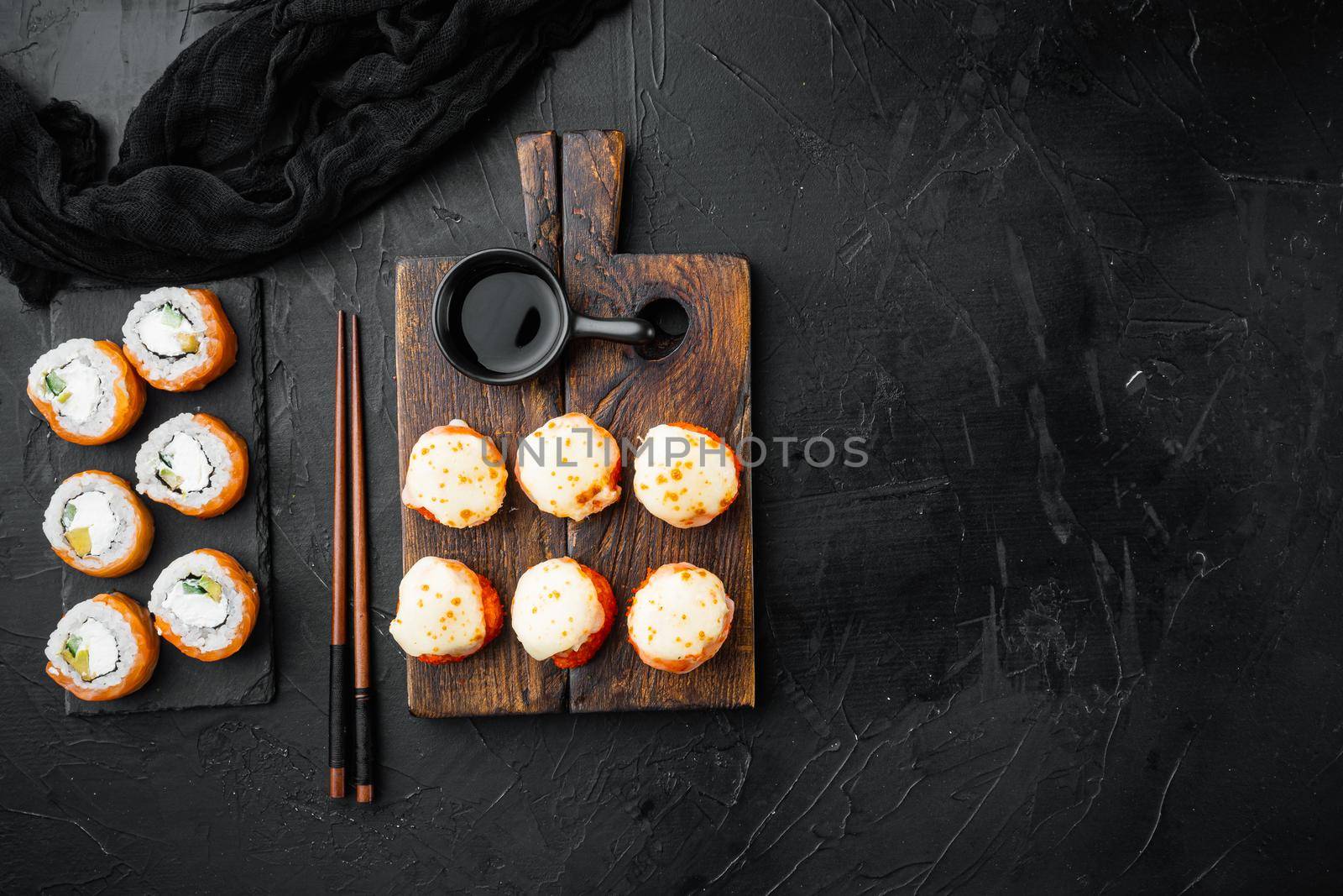 Sushi roll Geisha with fire scorched salmon, sea bass, shrimp, avocado set, on black stone background, top view flat lay , with copyspace and space for text