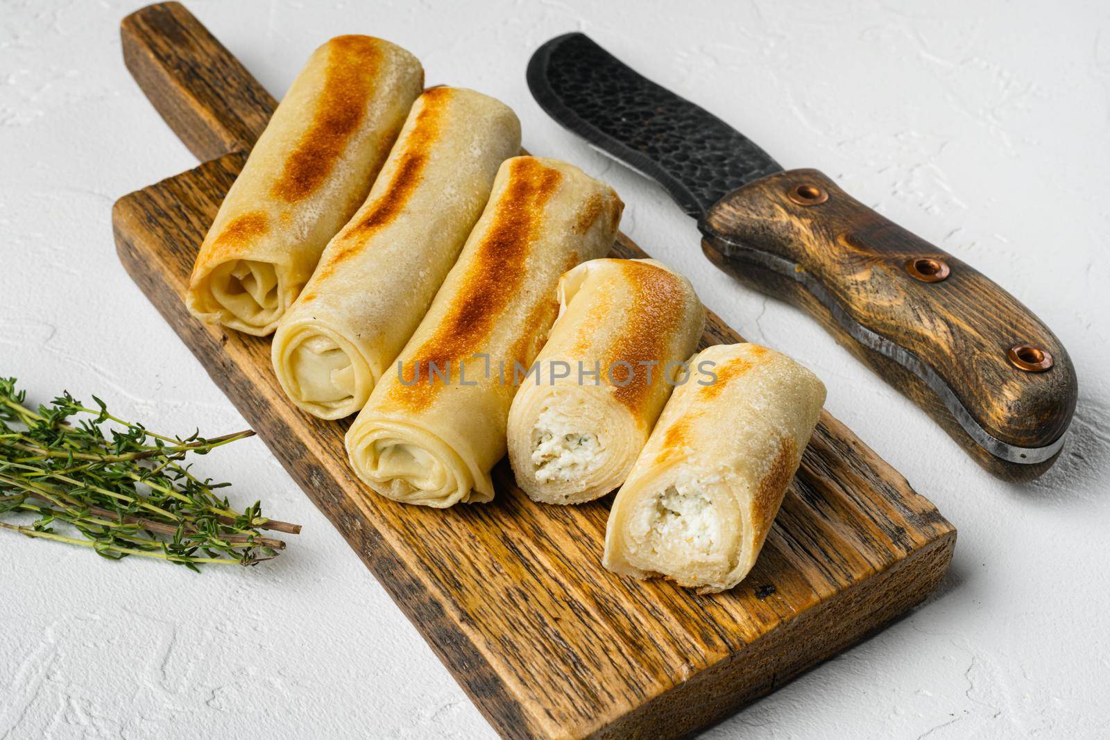Fried georgian crepes stuffed with suluguni, on white stone table background