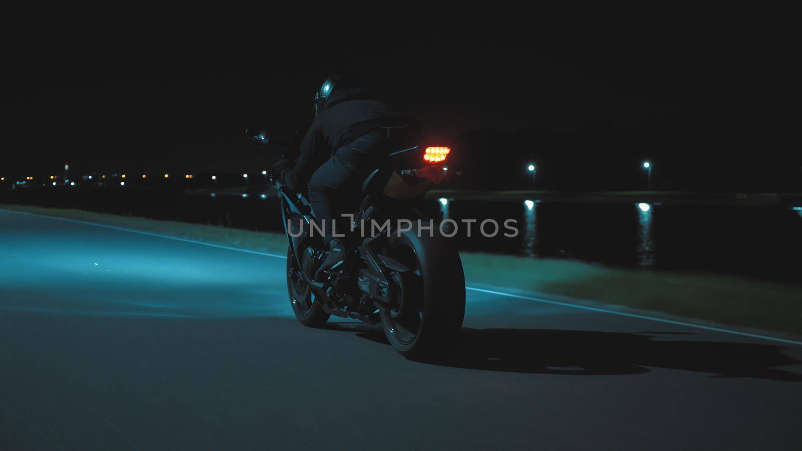 A man rides a sports motorcycle through the city at night against the backdrop of the river in 4k
