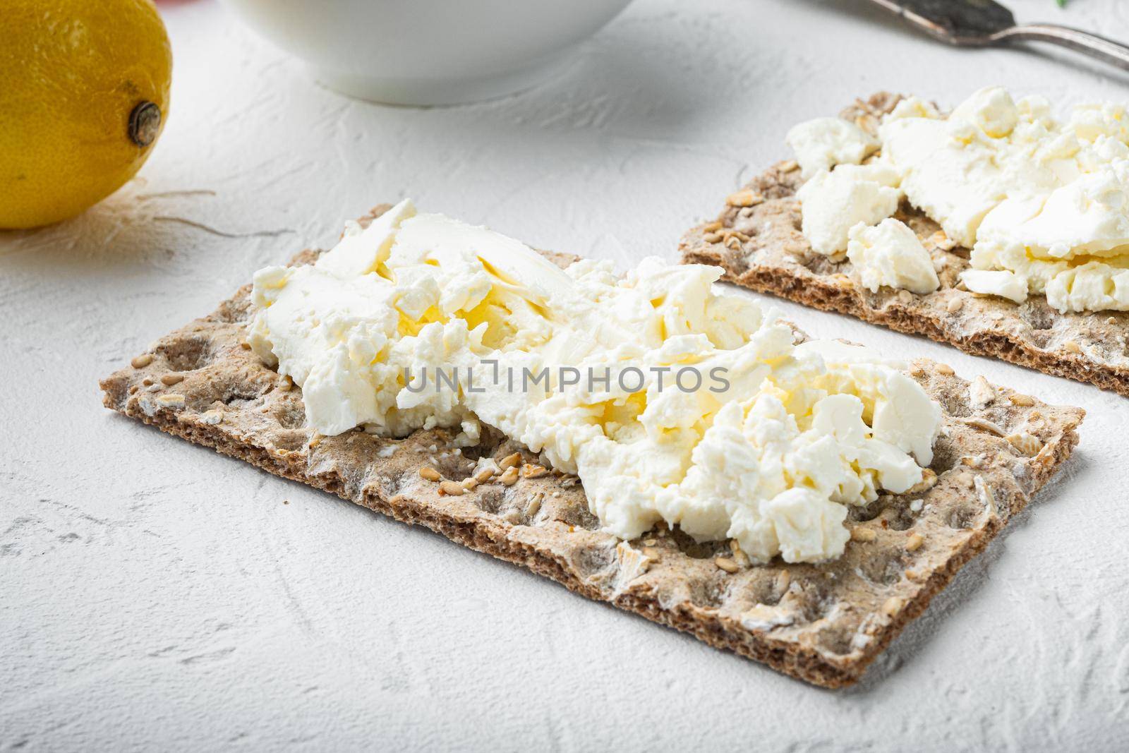 Fresh rye crispbreads with cream cheese set, on white stone table background, with copy space for text