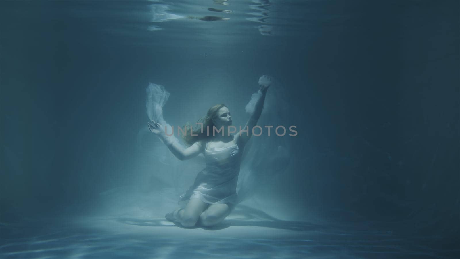 red-haired woman meditating underwater in white dress in 4k