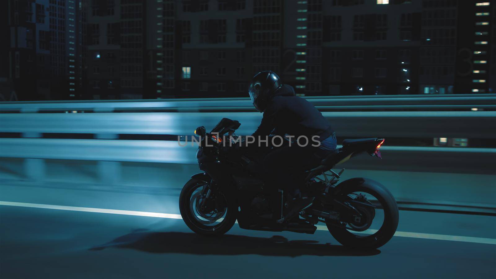 A man rides a sports motorcycle through the city at night in 4k