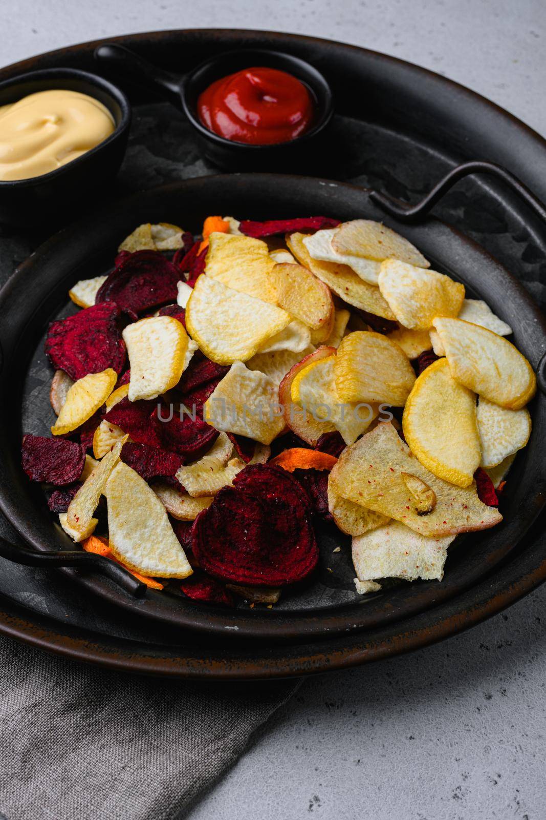 Dried vegetables chips, on gray stone table background by Ilianesolenyi