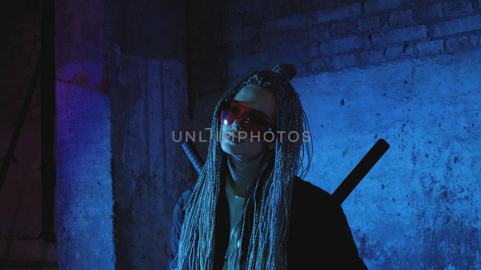 girl with dreadlocks and katanas in red glasses posing against a neon brick wall by studiodav