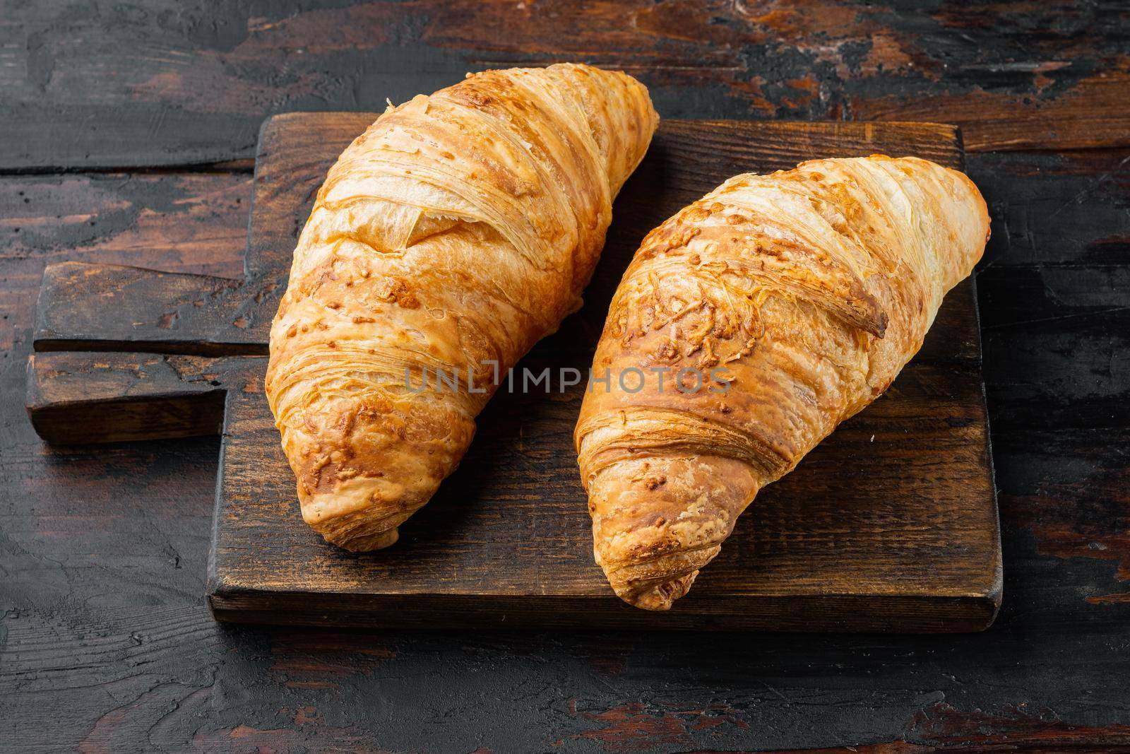 Freshly baked croissants, on old dark wooden table background by Ilianesolenyi