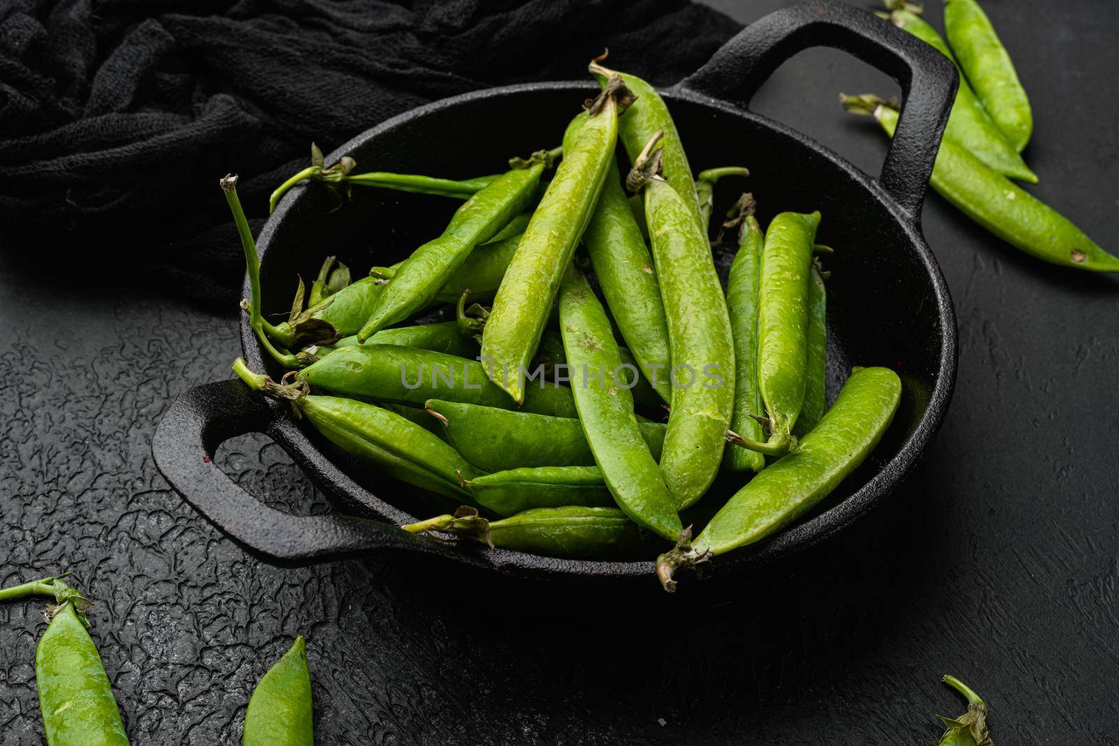 Raw Green Organic Snow Peas, on black dark stone table background