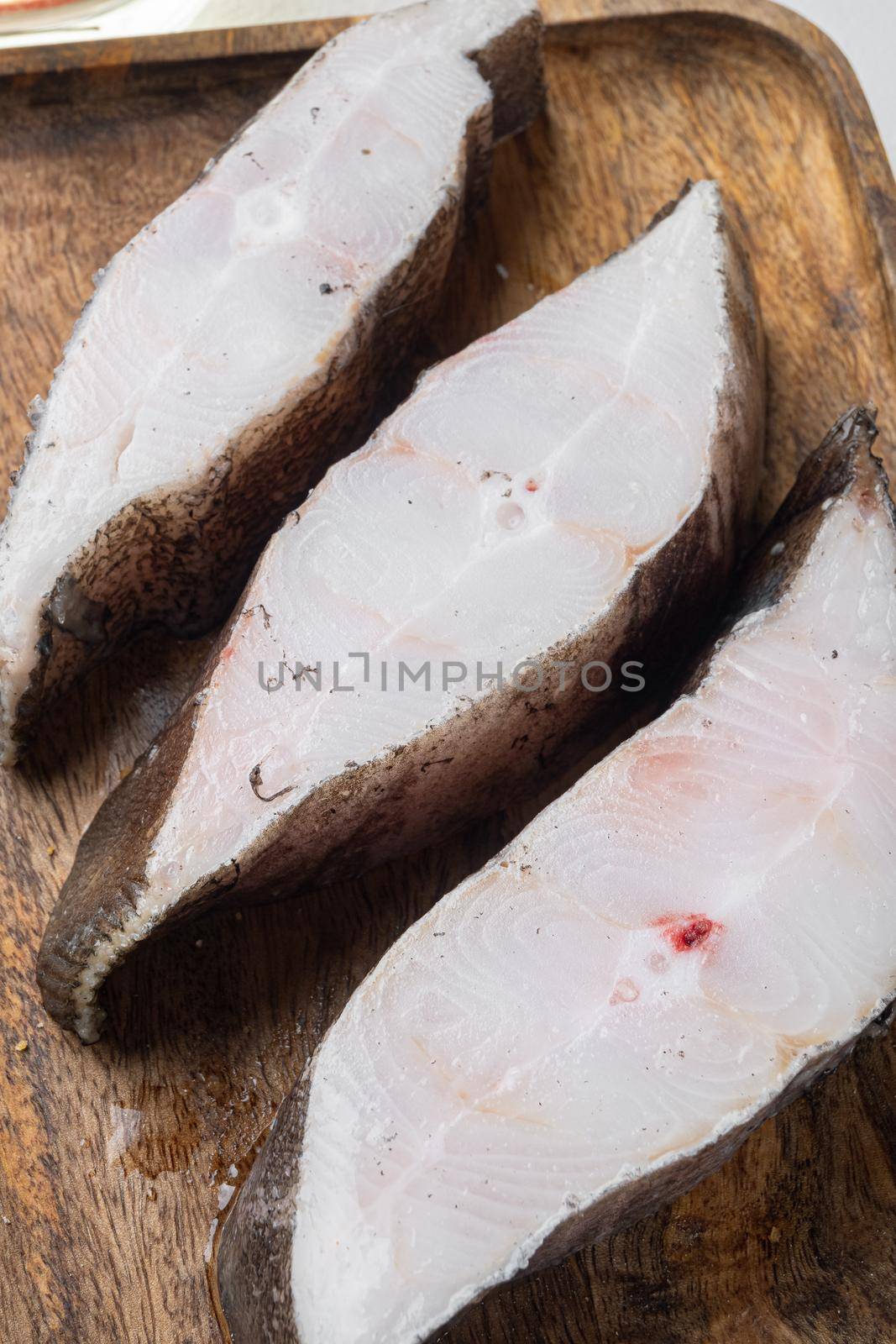 Chilled halibut steaks set, with ingredients and rosemary herbs, on white stone table background