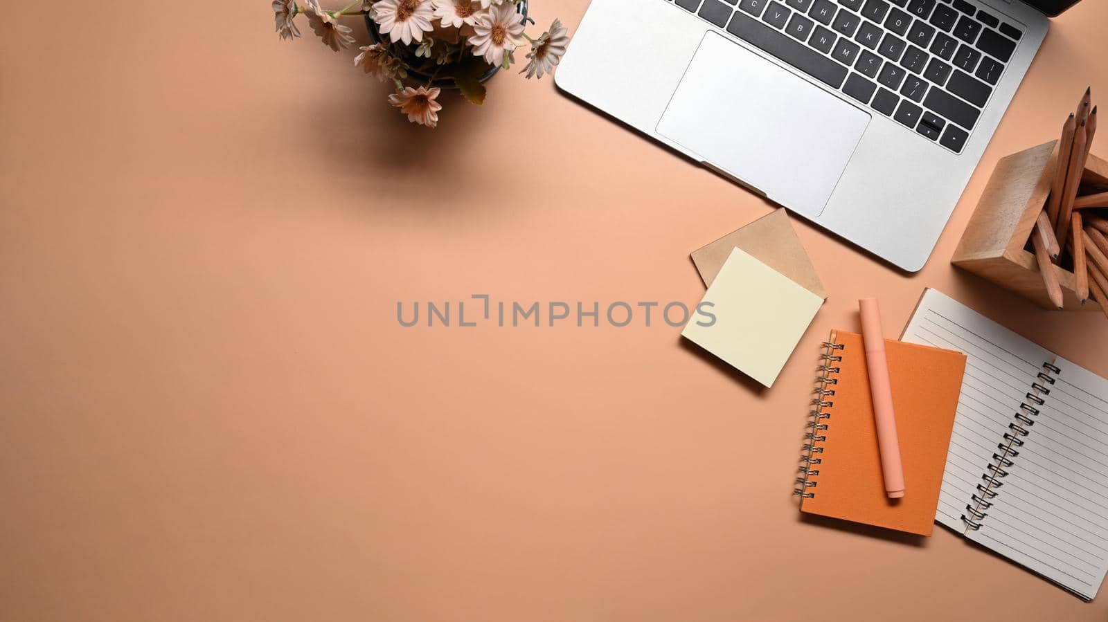 Laptop computer, notebook, sticky notes and pencil holder on beige background. by prathanchorruangsak