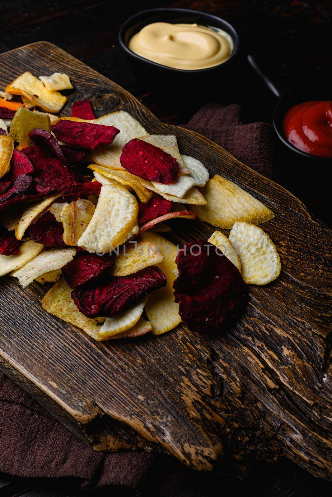 Dried vegetables chips, on black wooden table background by Ilianesolenyi