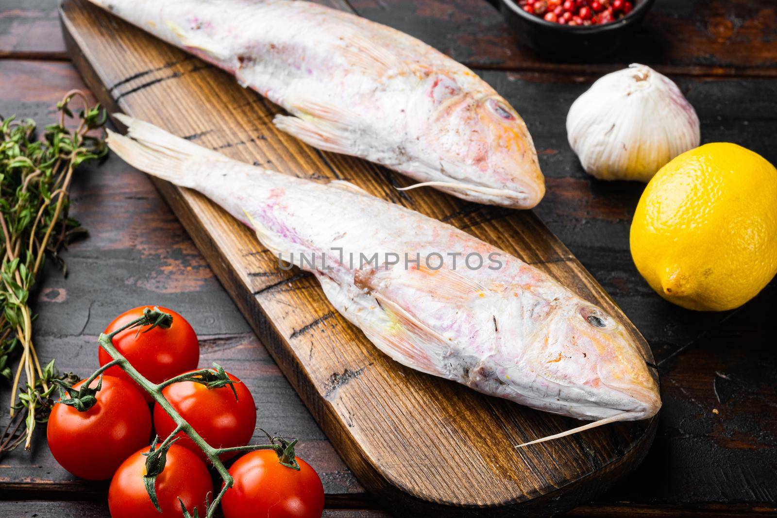 Raw fresh mullet or barabulka whole fish, with ingredients and herbs, on old dark wooden table background by Ilianesolenyi