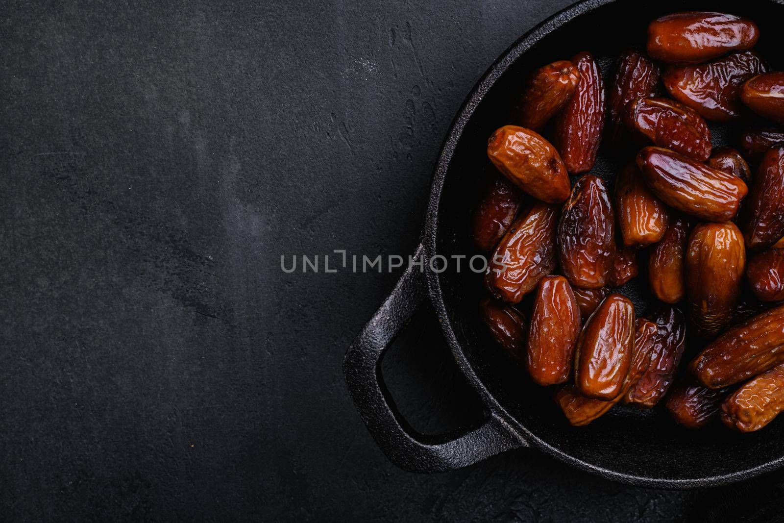 Dried date palm fruits set, on black dark stone table background, top view flat lay, with copy space for text by Ilianesolenyi