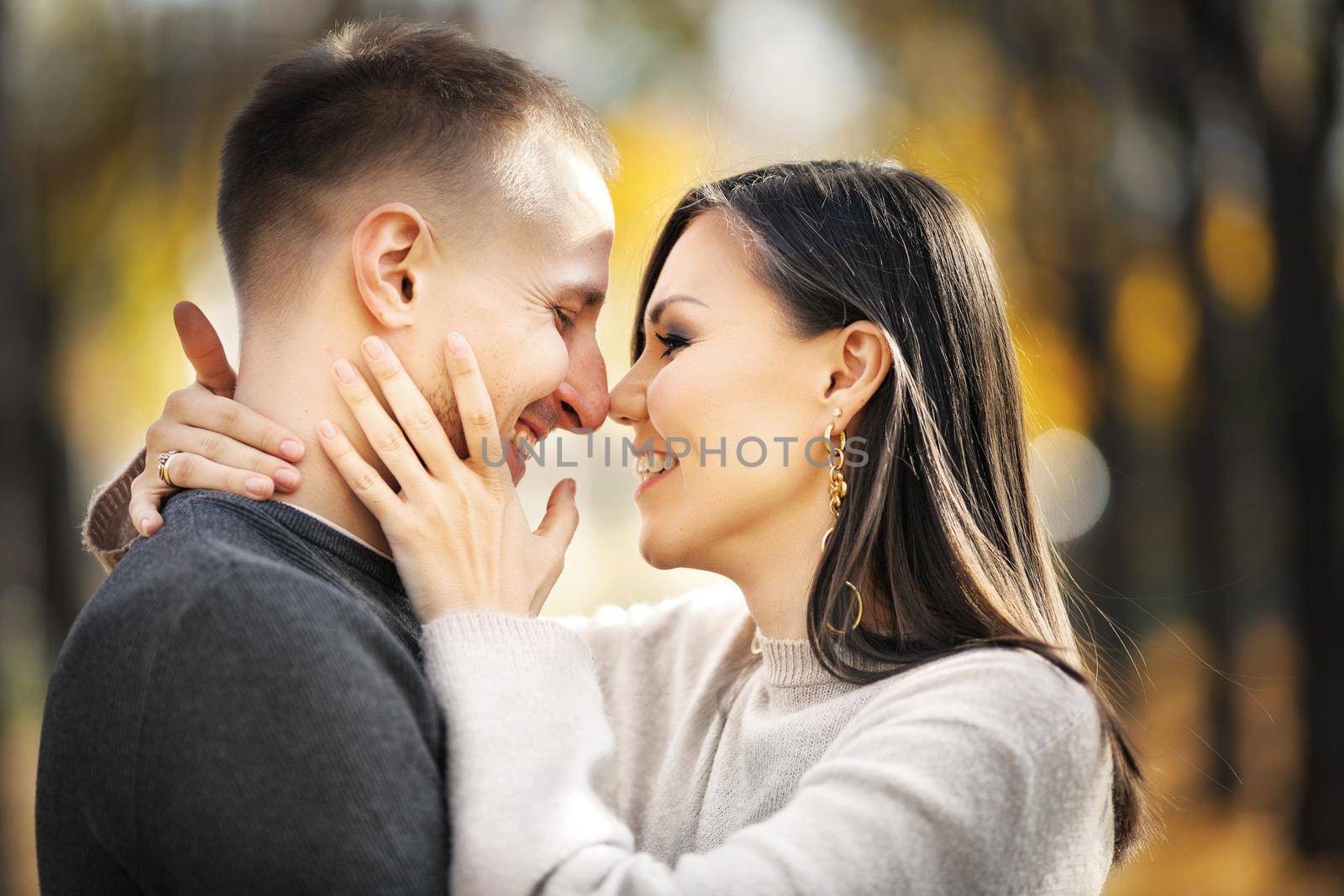 Portrait of a happy mixed race couple of lovers on a date laughing and hugging in autumn park.