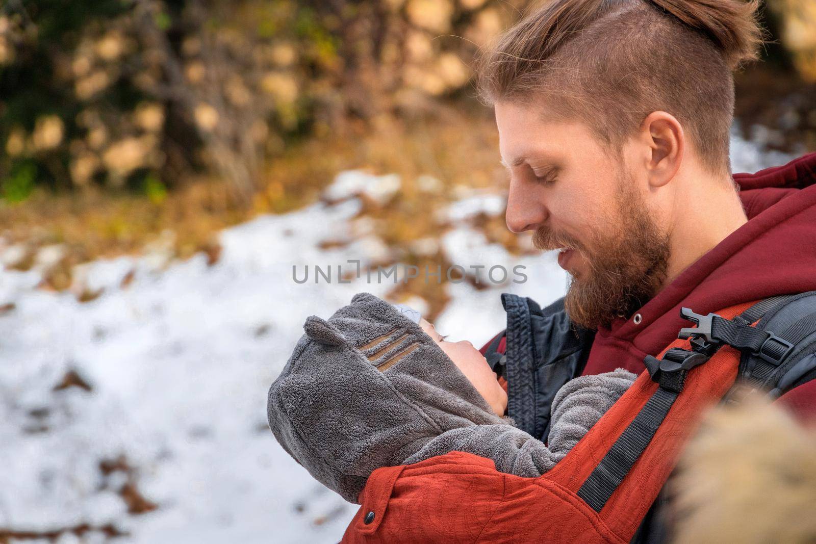 Babywearing man is carrying him child and travel in autumn nature.