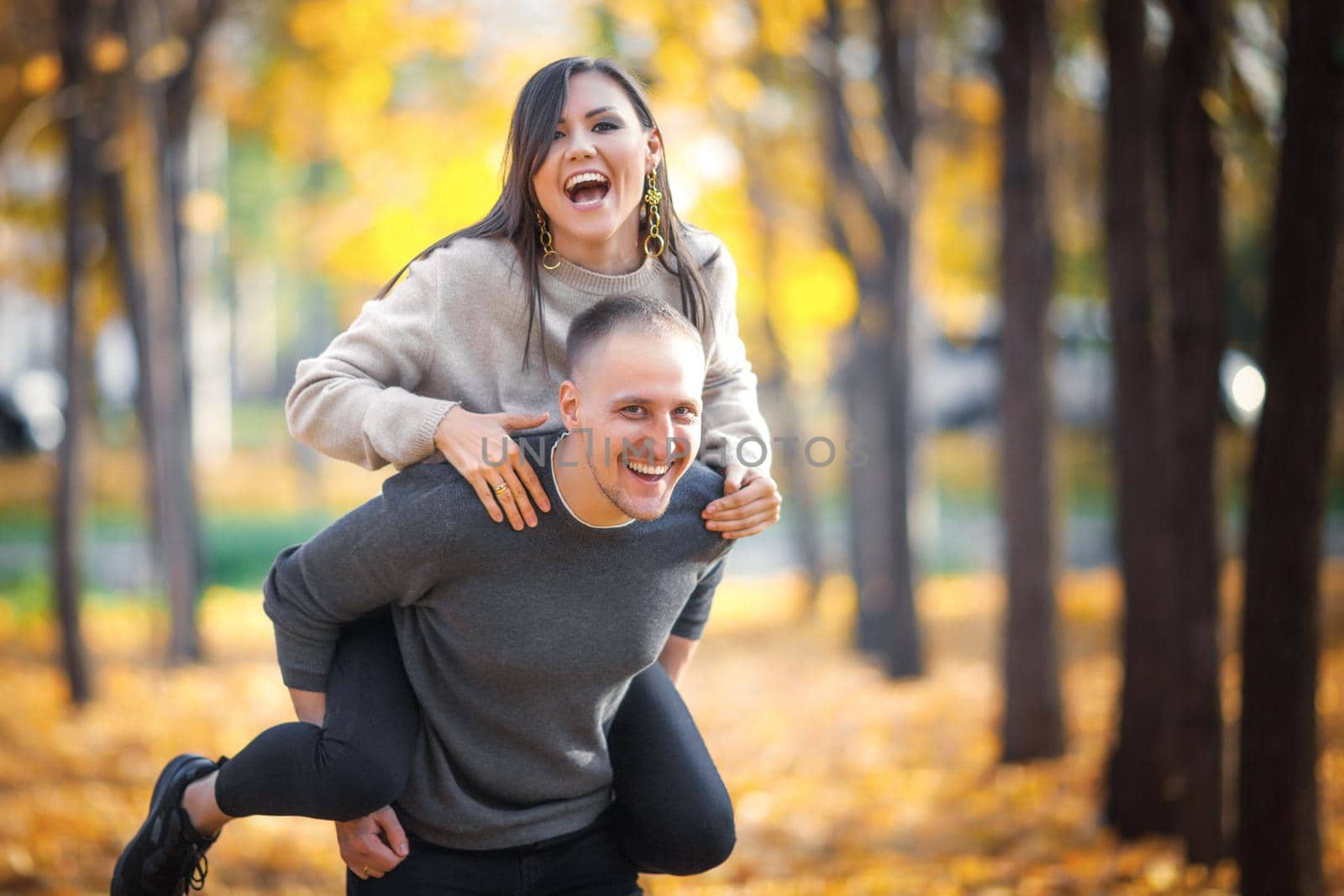 Happy young couple have fun and enjoy outdoor recreation on the autumn city park.