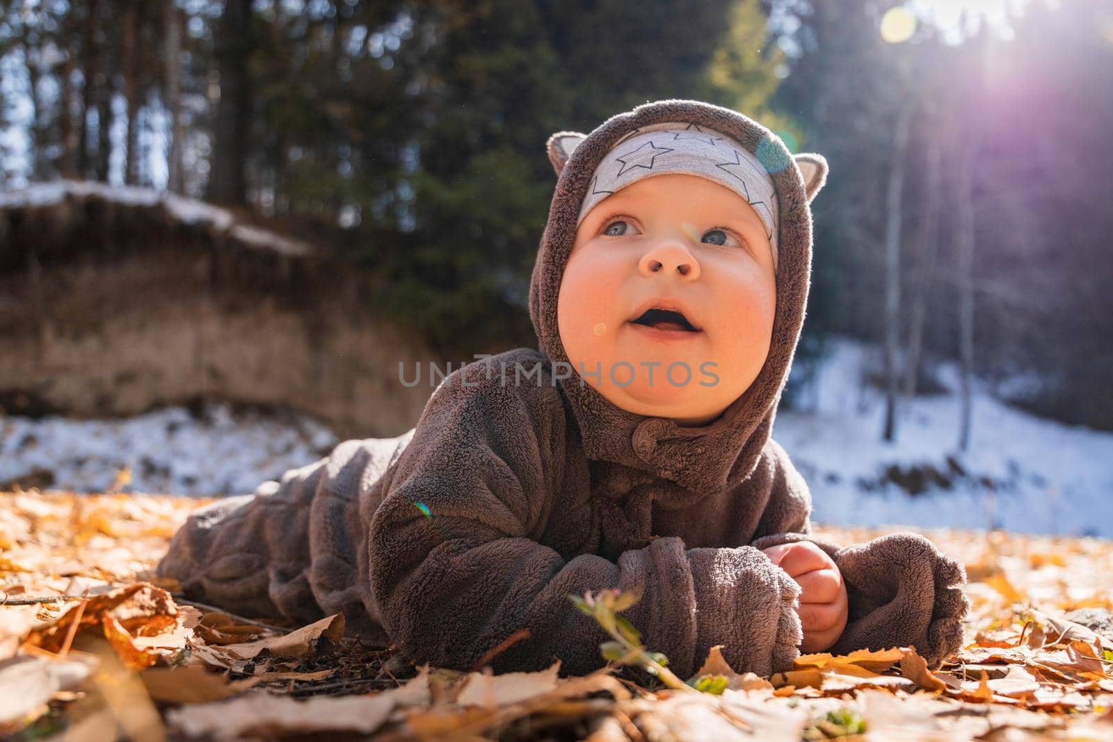 Little laughing baby boy playing in yellow foliage. Autumn in the city park.