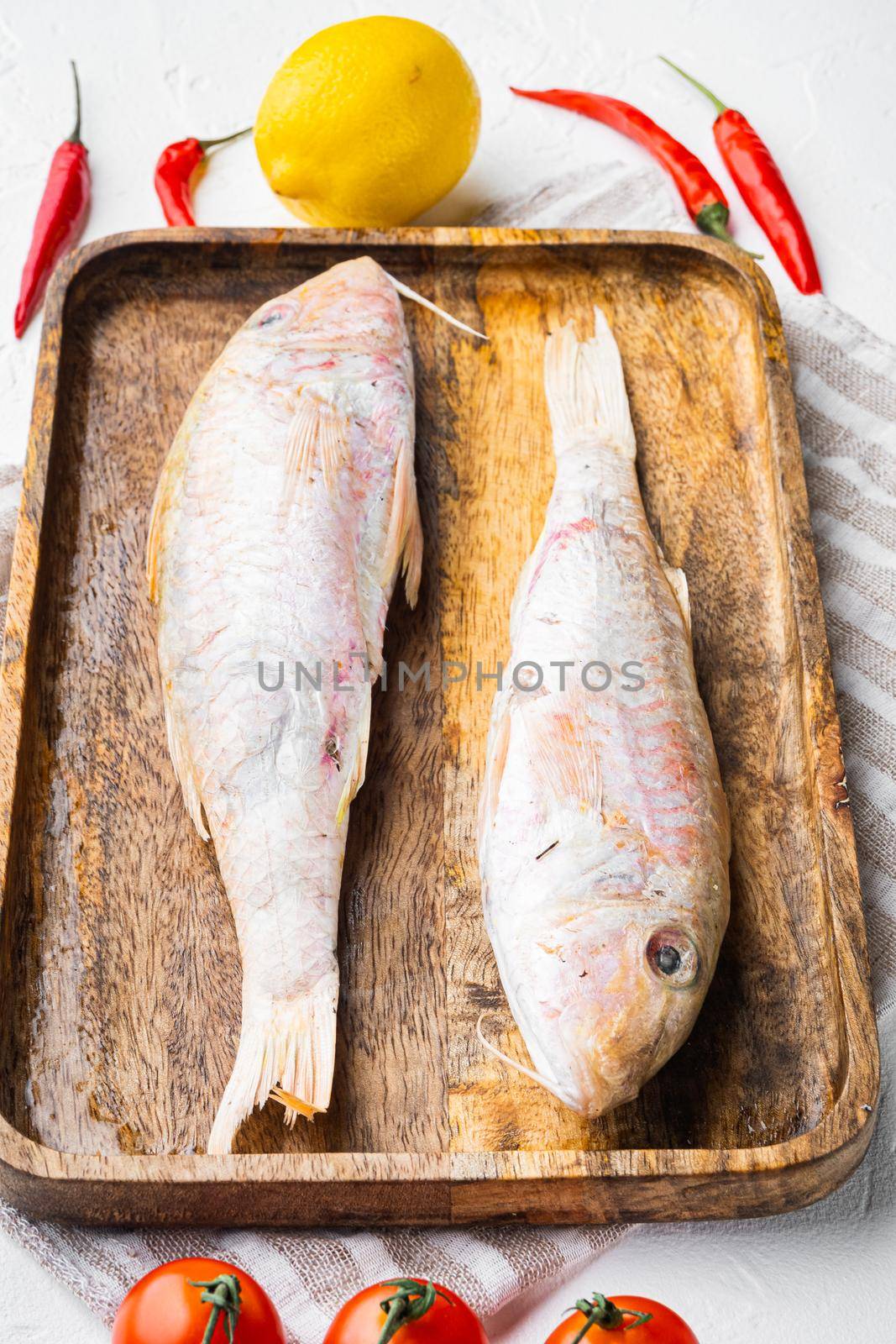 Raw fresh mullet or barabulka whole fish set, with ingredients and herbs, on white stone table background