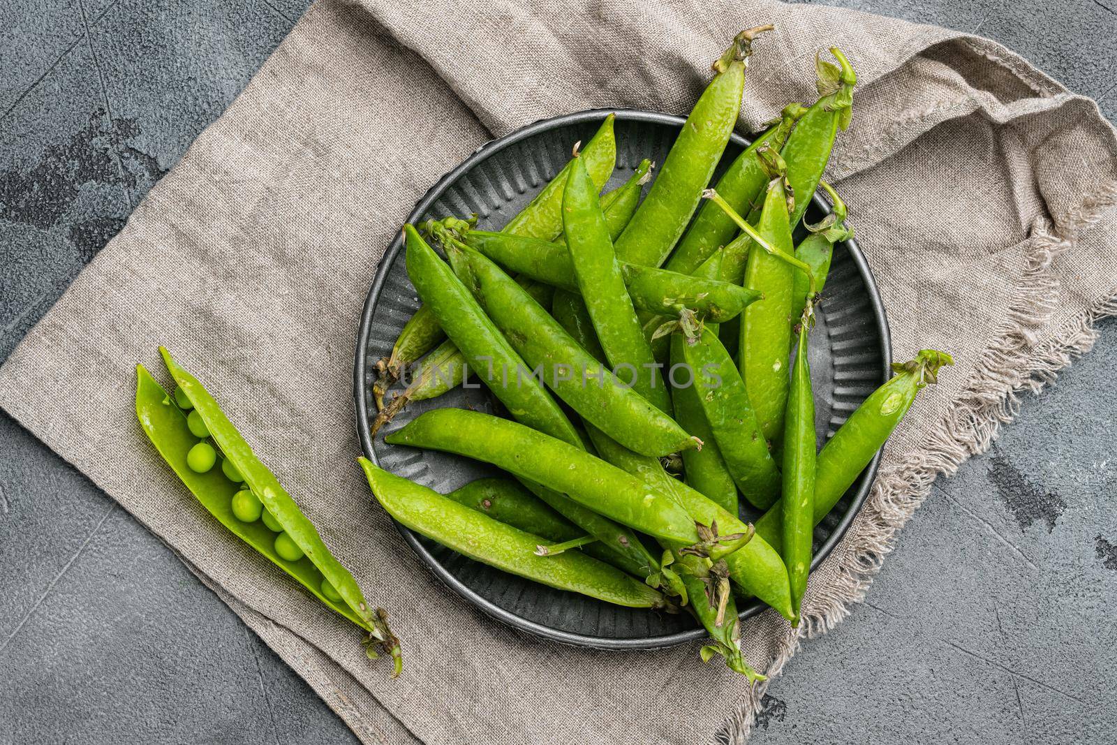 Green peas Freshly harvested on gray stone table background, top view flat lay by Ilianesolenyi