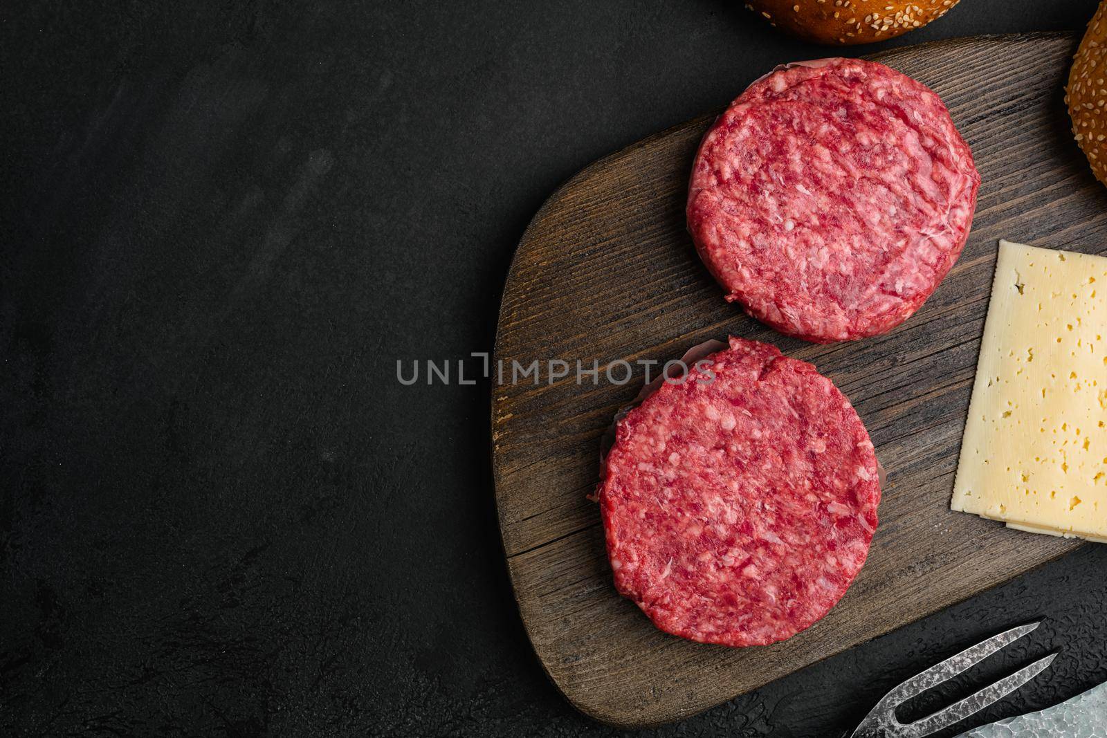 Burger Patty, ground beef meat on black dark stone table background, top view flat lay, with copy space for text by Ilianesolenyi