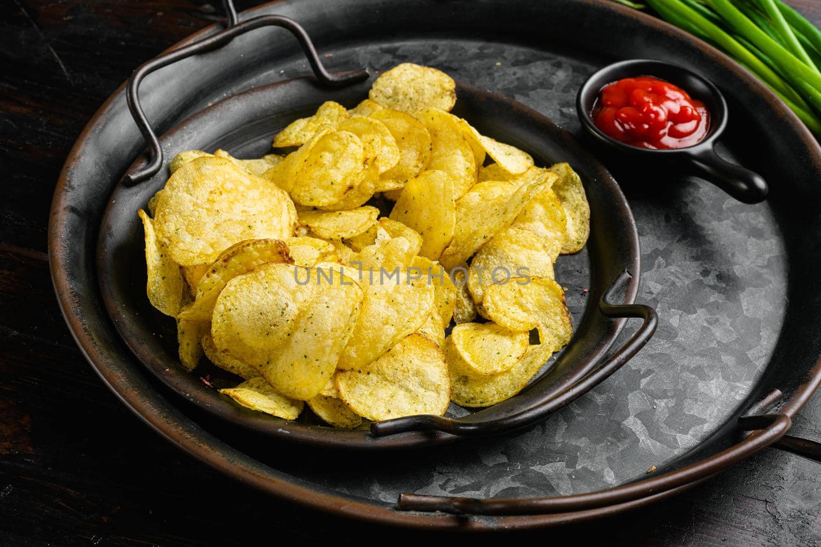 Home made potato chips, on old dark wooden table background