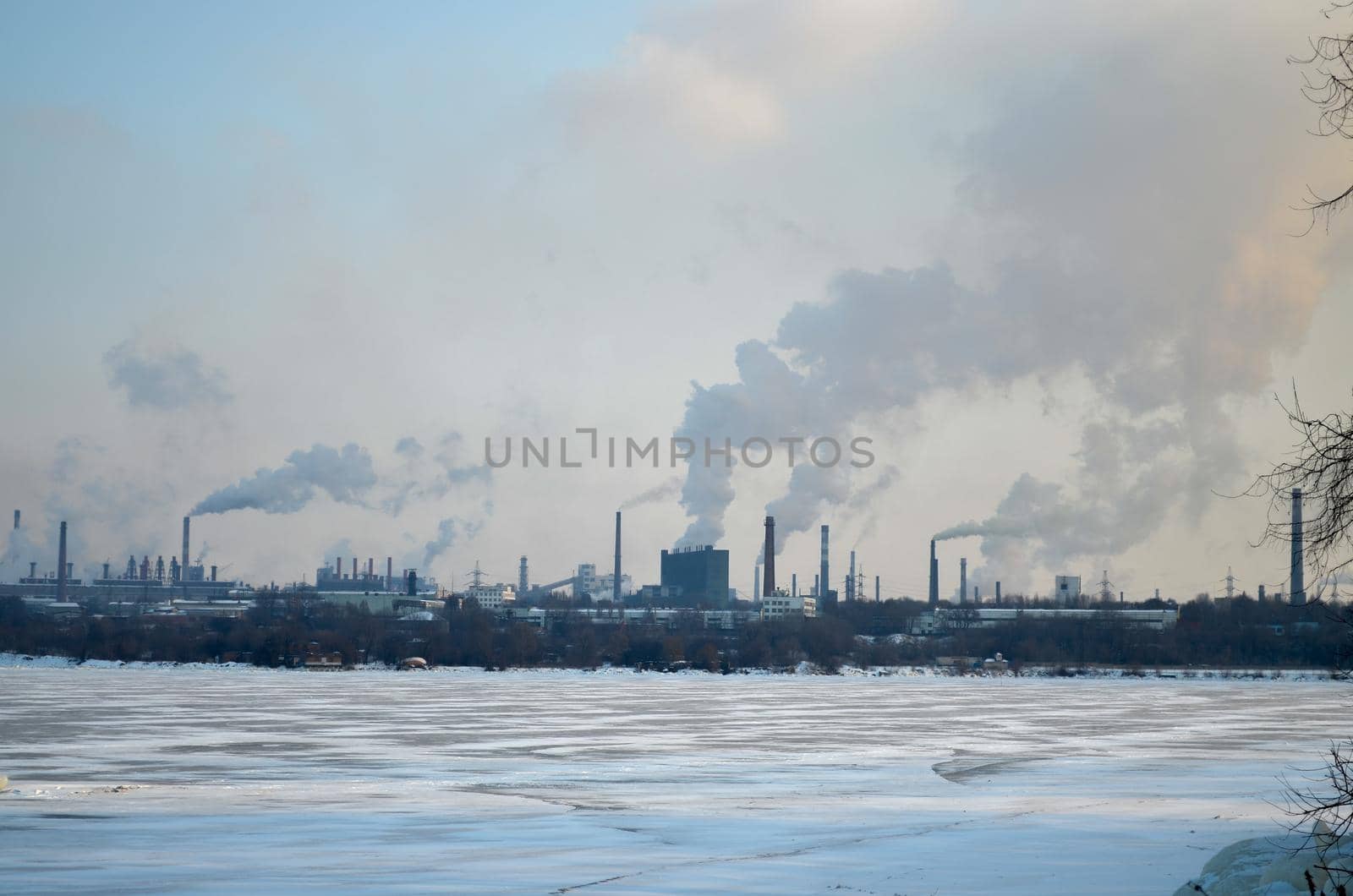 Plants and factories with smoke from chimneys. Air pollution concept. Industrial city, smoking plant, frozen river