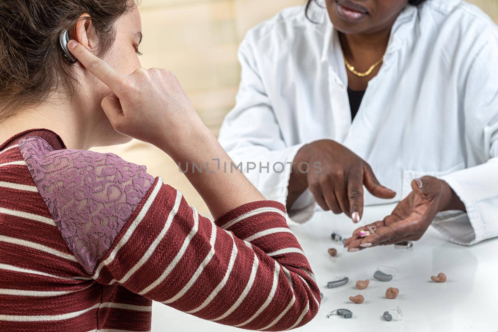 Patient trying different types of hearing aids. dialoguing with his hearing aid worker