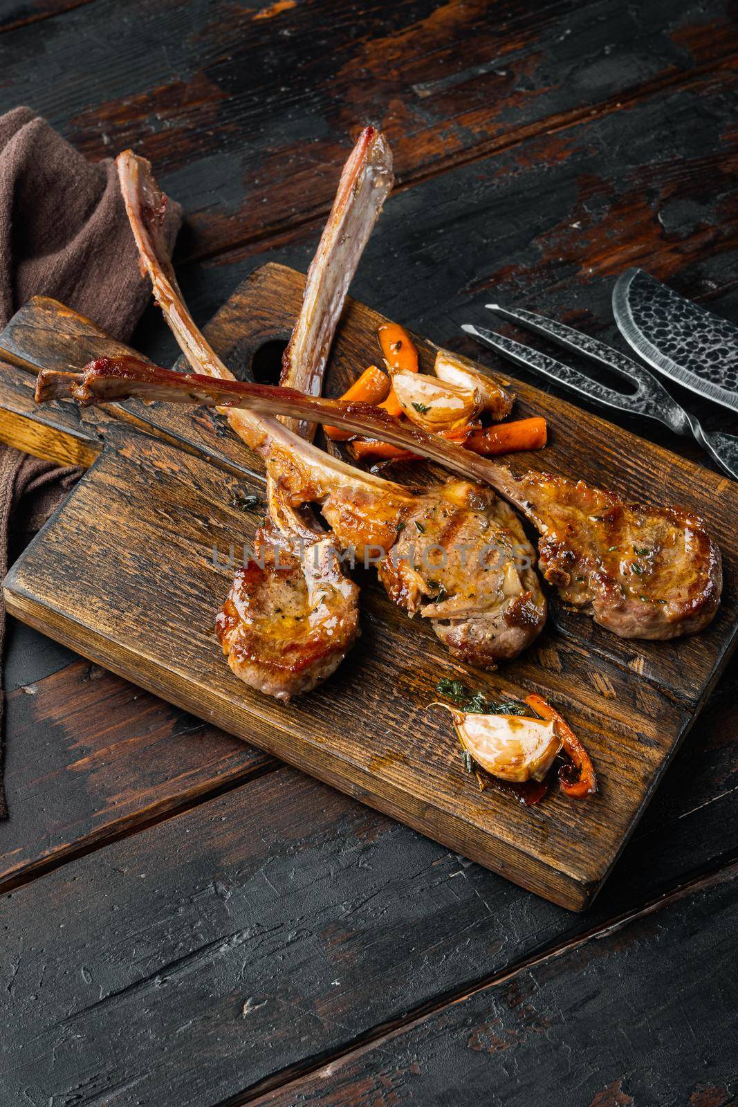 Homemade Cooked Lamb Chops with garlic and Carrots, on wooden serving board, on old dark wooden table background , with copyspace and space for text by Ilianesolenyi