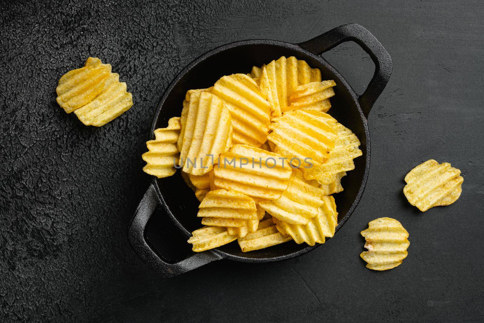 Wavy Ranch Flavored Potato Chips, on black dark stone table background, top view flat lay