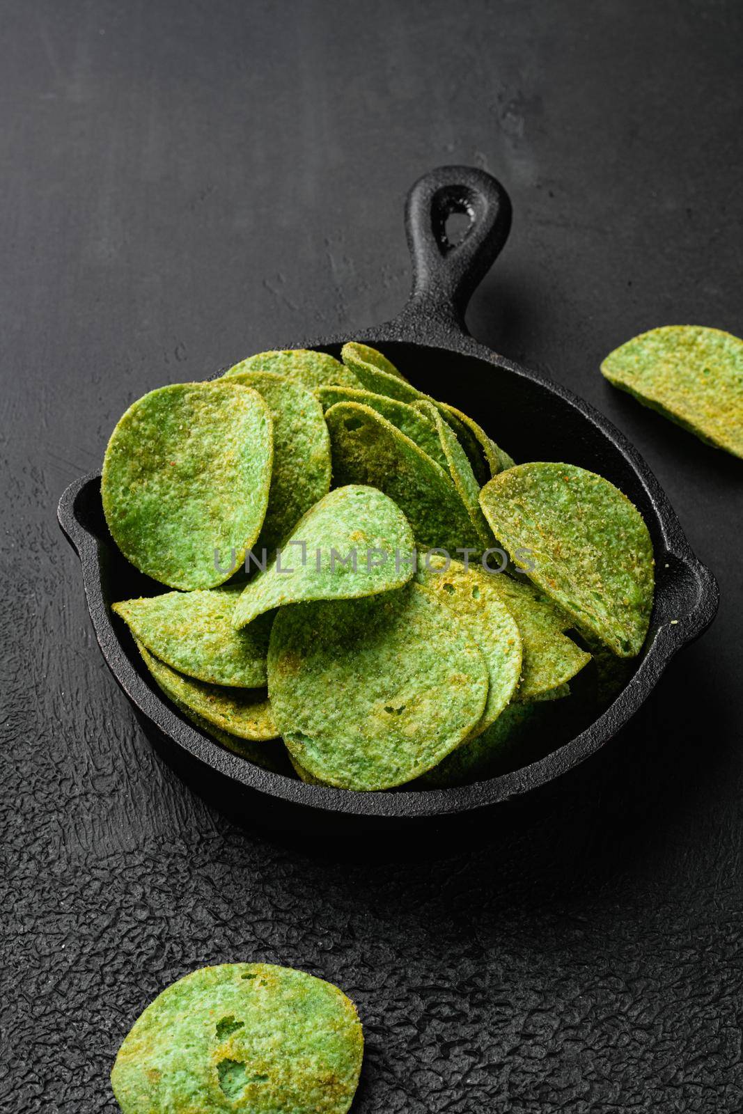 Green Chile Limon Flavored Potato Chips on black dark stone table background by Ilianesolenyi