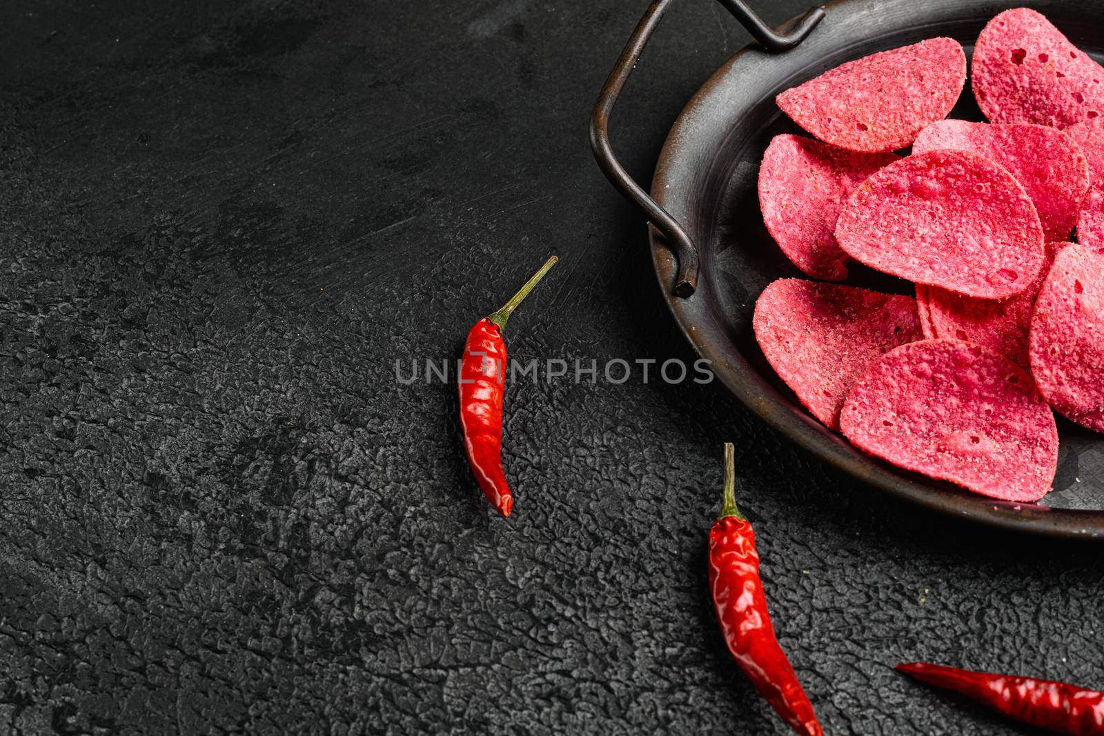 Adobadas Flavored red Potato Chips on black dark stone table background, with copy space for text by Ilianesolenyi