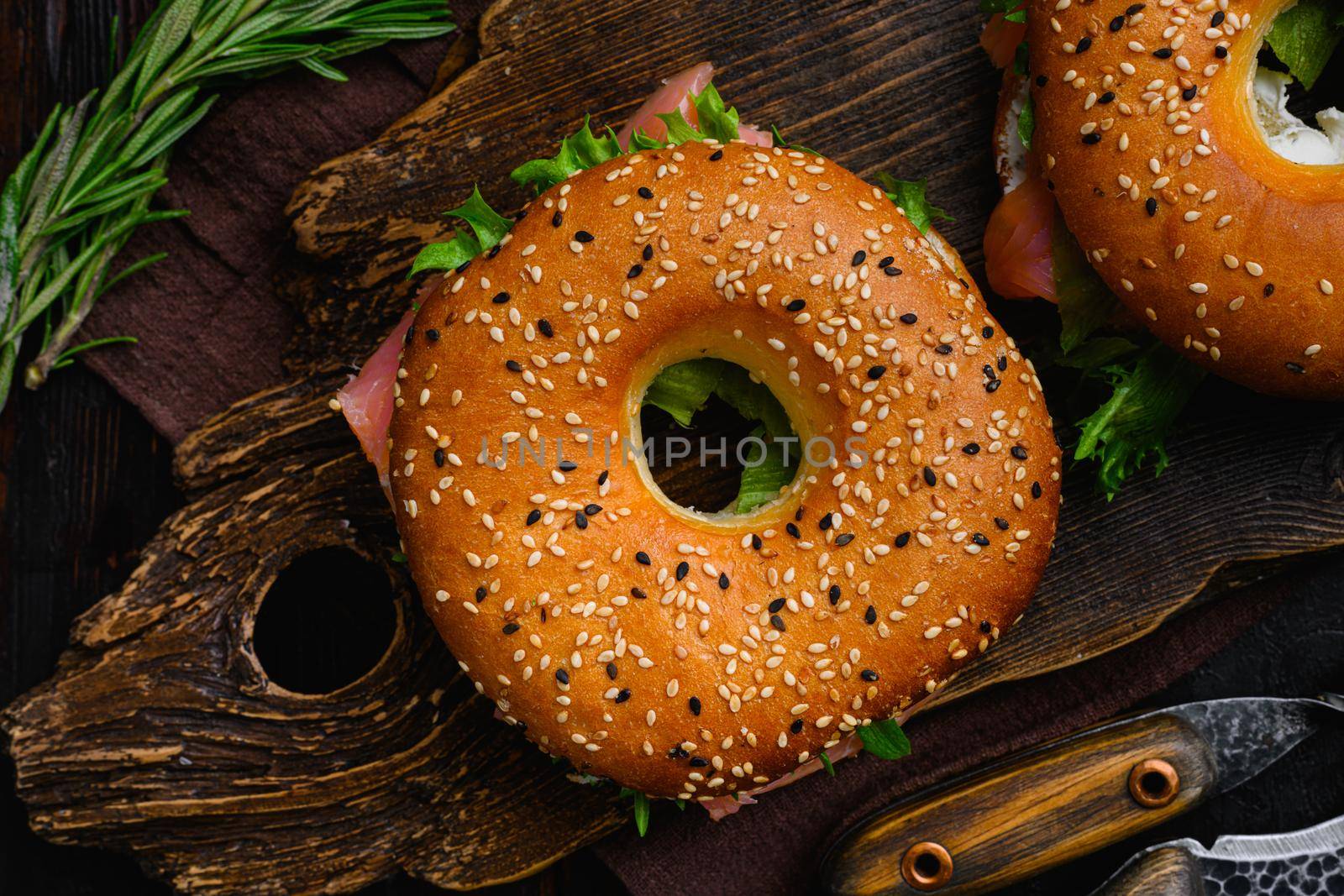 Fresh Smoked Salmon And Cream Cheese Bagel, on old dark wooden table background, top view flat lay by Ilianesolenyi