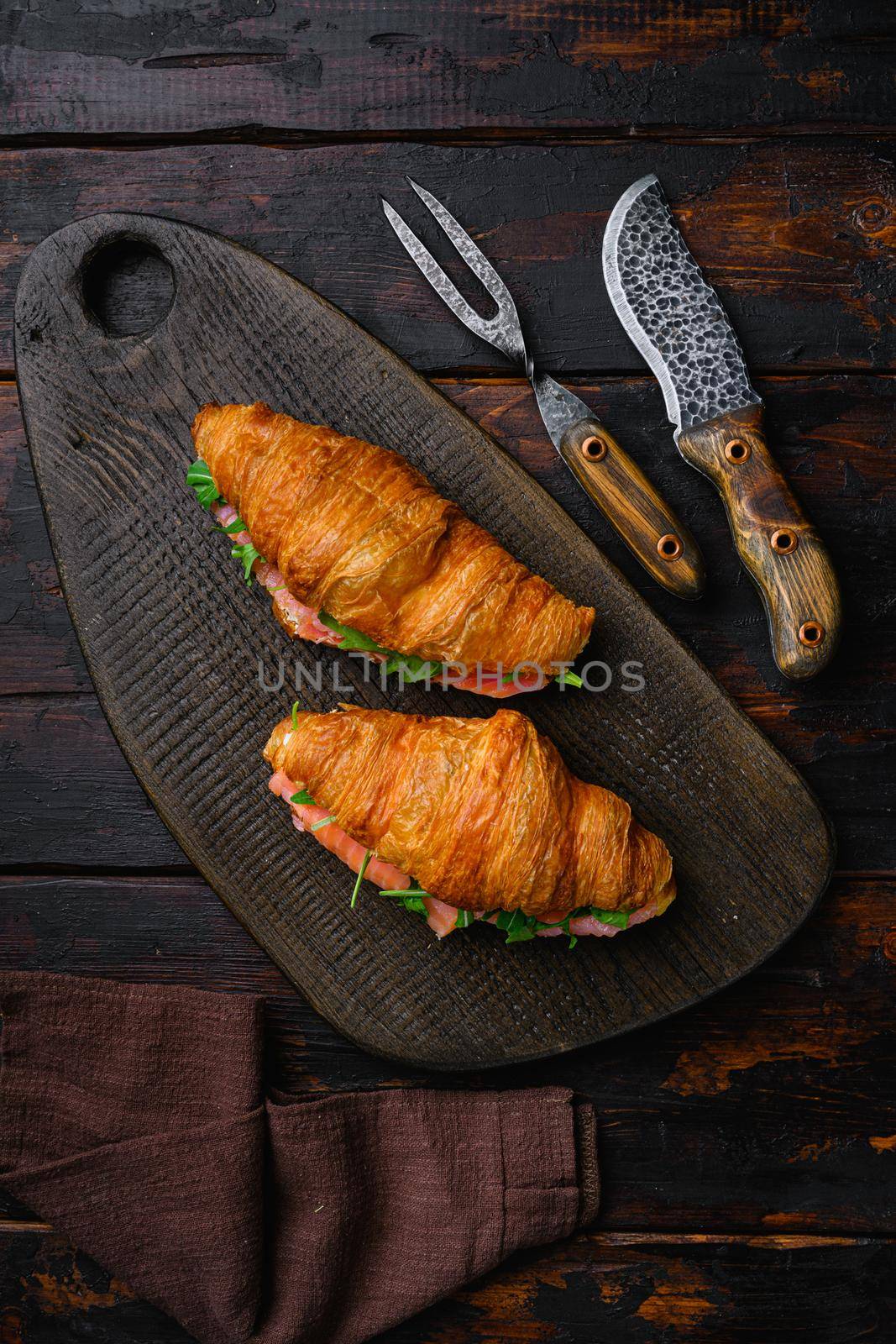Croissant sandwich with salmon, on old dark wooden table background, top view flat lay by Ilianesolenyi