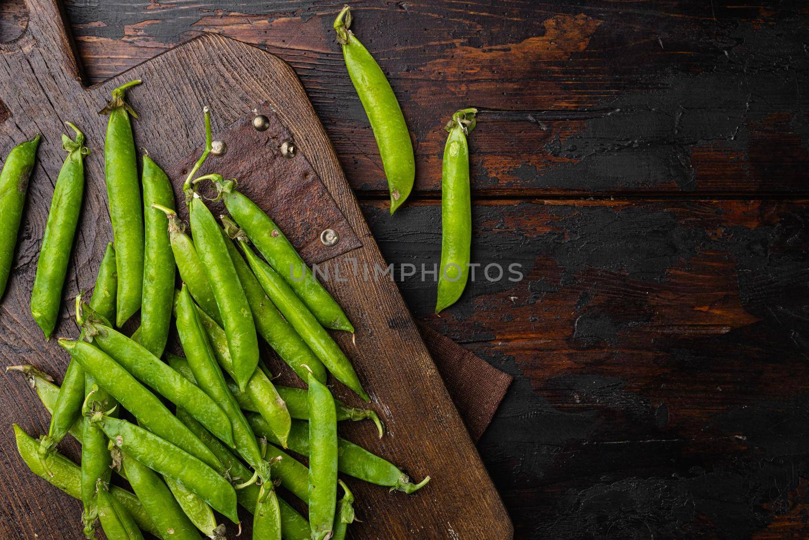 Green pea pod on old dark wooden table background, top view flat lay by Ilianesolenyi