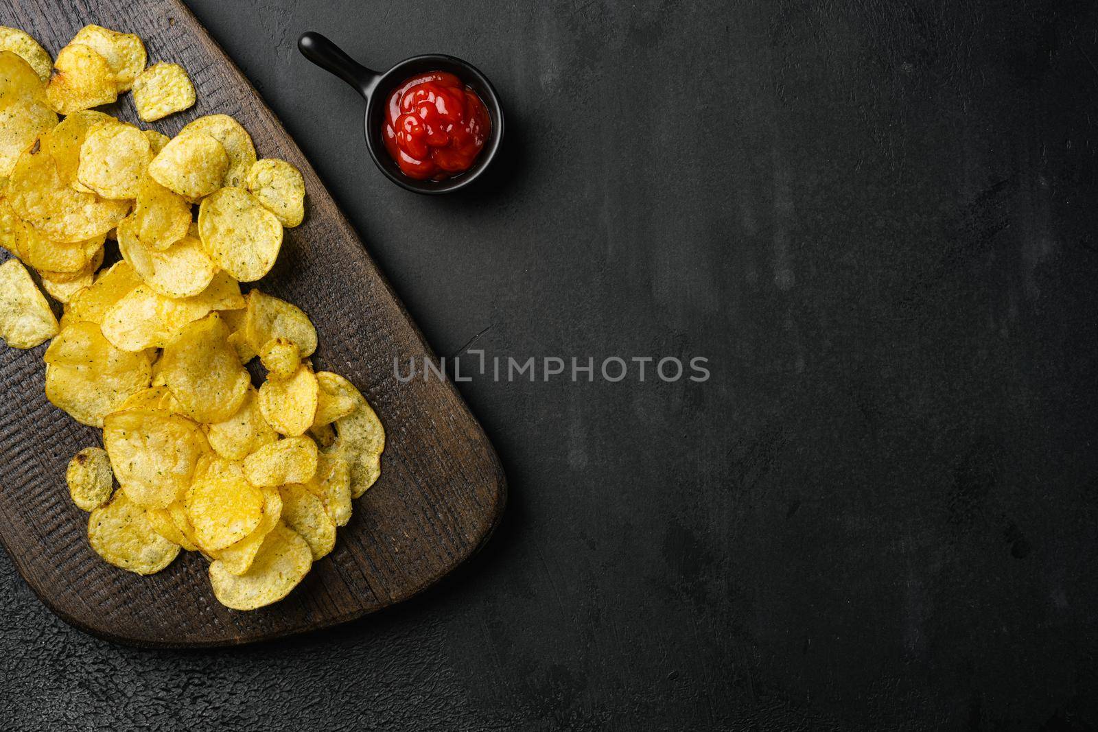 Chesapeake Bay Crab Spice Flavored Potato Chips, on black dark stone table background, top view flat lay, with copy space for text